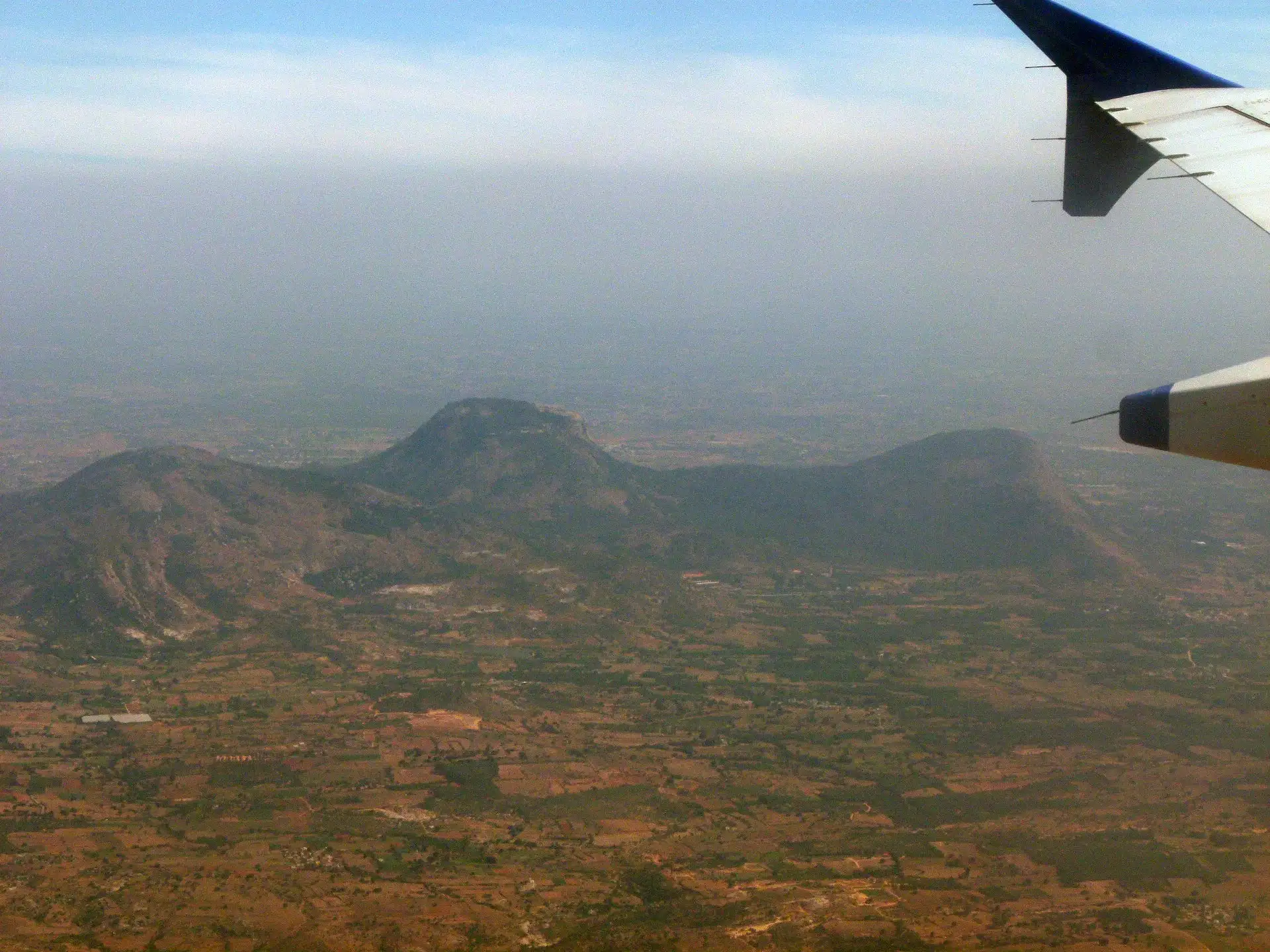 Nandi Hills rising above the brown farmland of the Deccan plateau, seen from an aircraft window