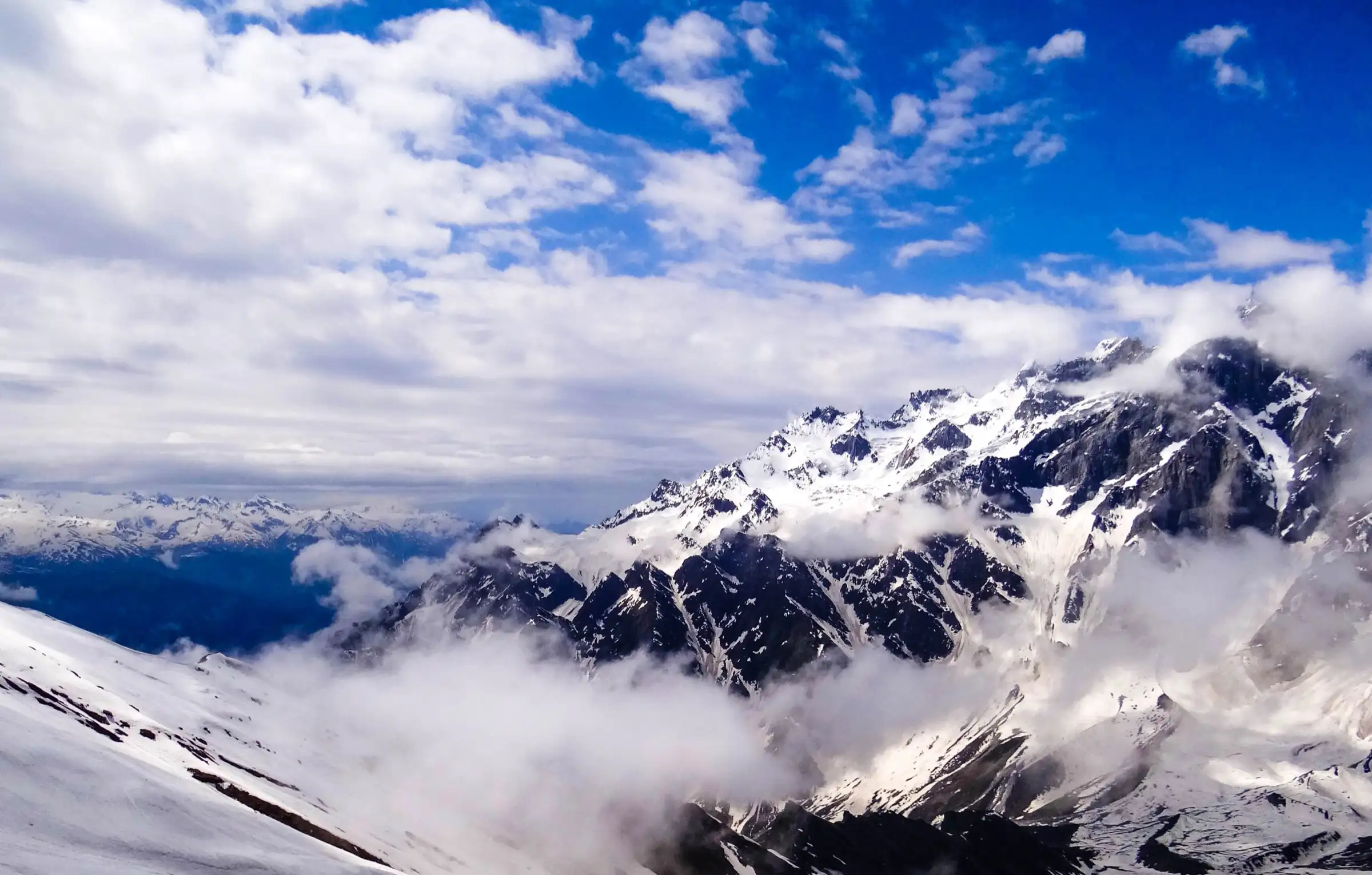 Snow-covered Pir Panjal peaks rising out of cloud, photographed from the snow slopes at Bakarthach above Solang