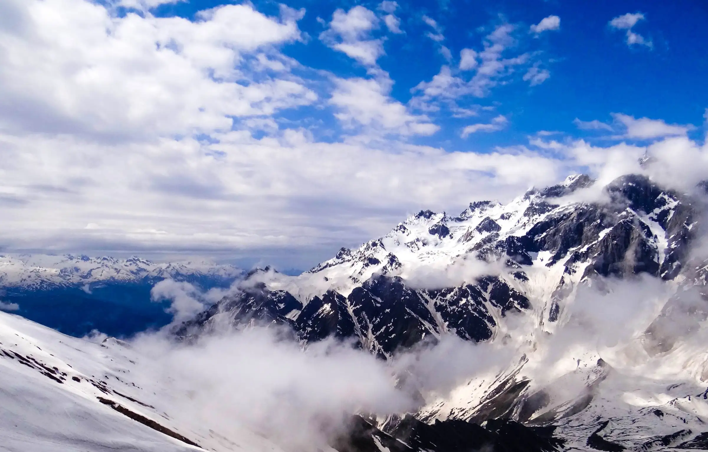 Snow-covered Pir Panjal peaks rising out of cloud, photographed from the snow slopes at Bakarthach above Solang