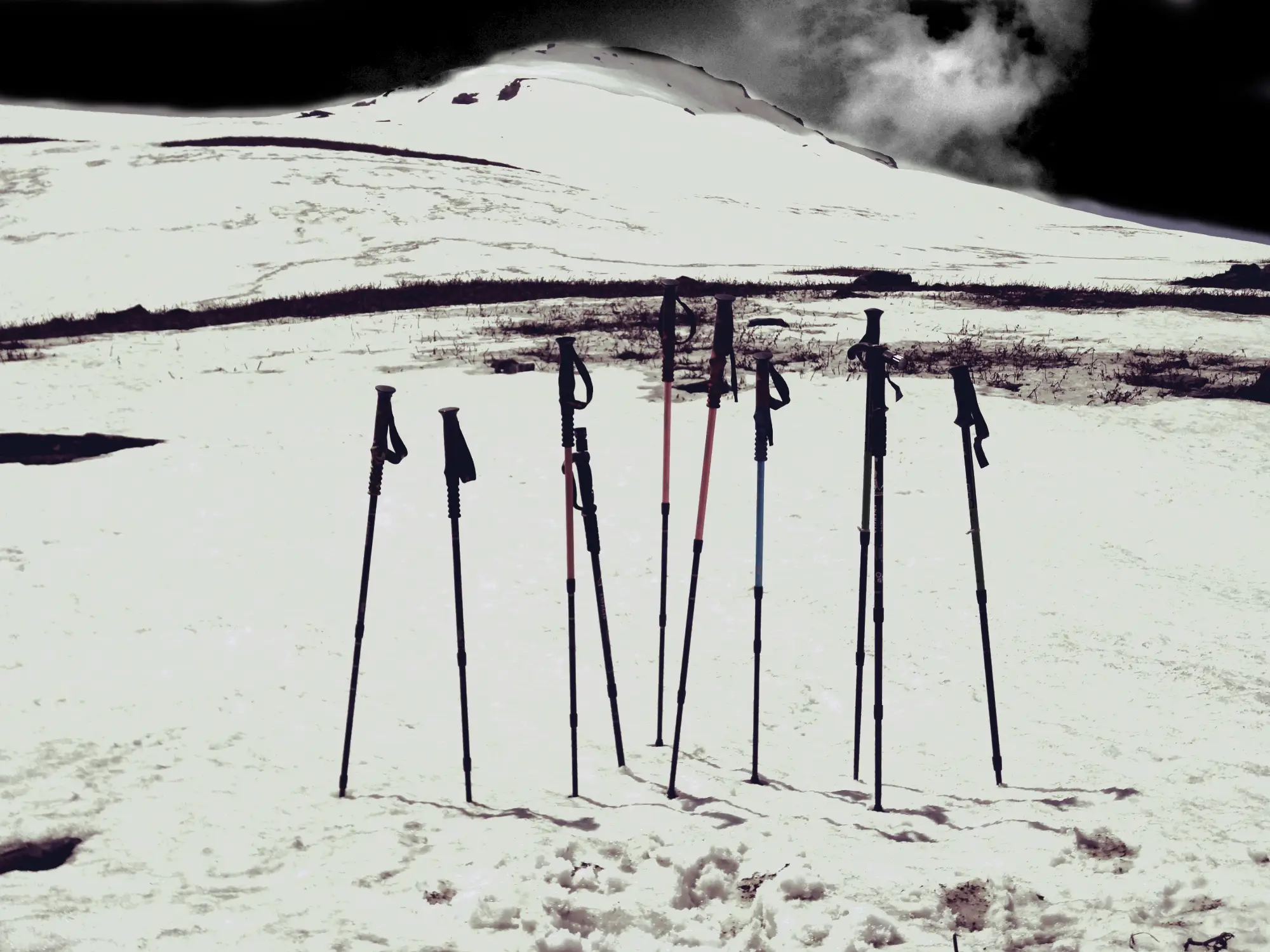 Trekking poles standing in snow below the white slope of Baluni Top on the Sunderdhunga trek