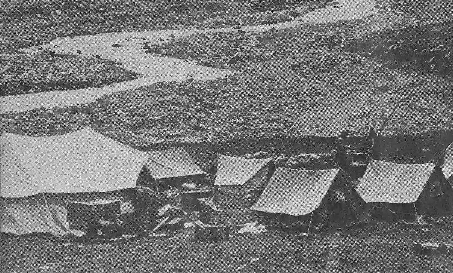 Black-and-white 1939 photograph of the Polish expedition's base camp tents beside a braided glacial stream in the valley below Nanda Devi East