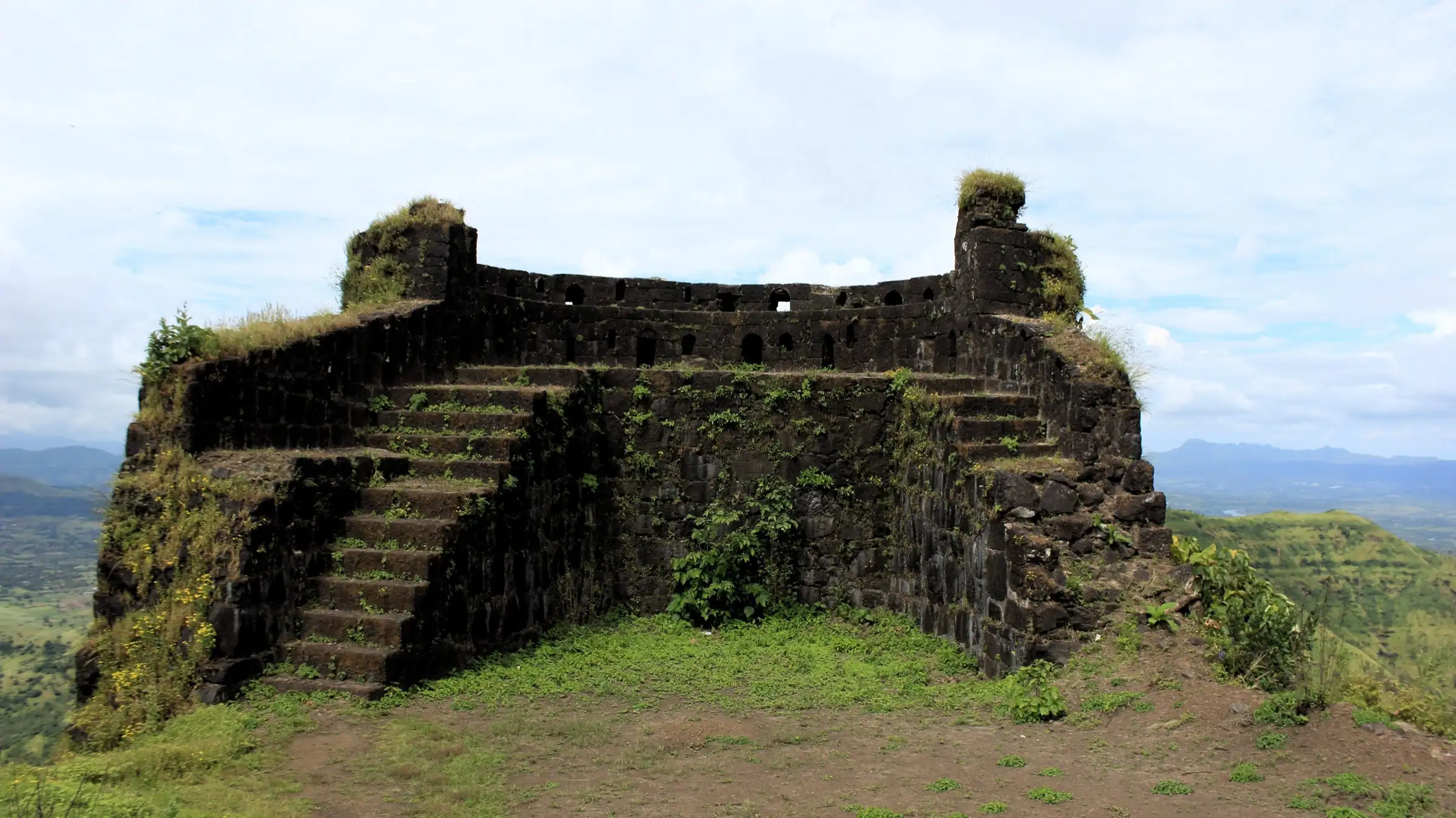 A large dark-stone bastion on Rohida fort with steps up to its loopholed parapet