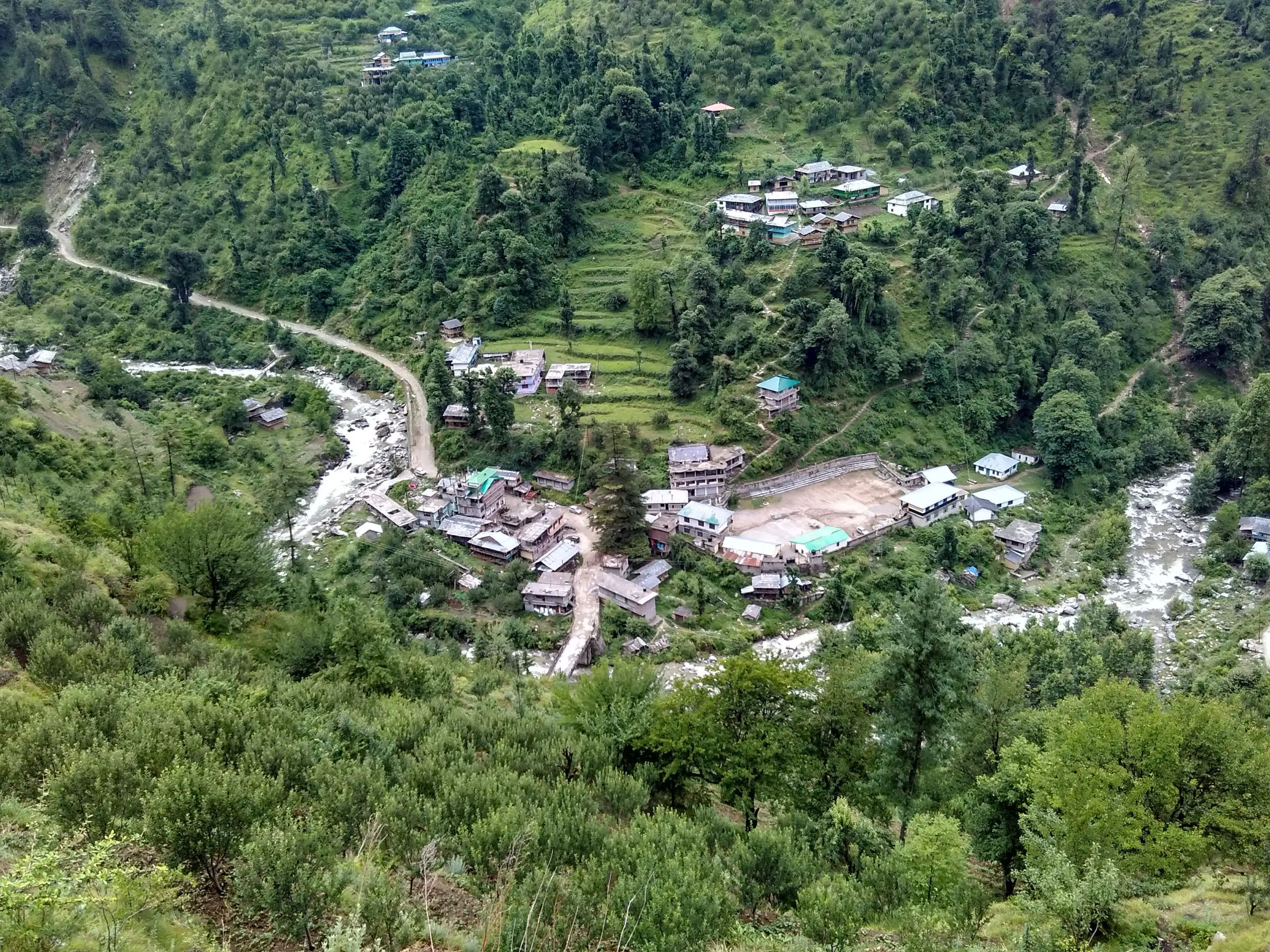 Bathad village, the starting point of the Bashleo Pass trek, seen from above: houses and terraced fields where the Palachan stream meets the road, with forested slopes all round