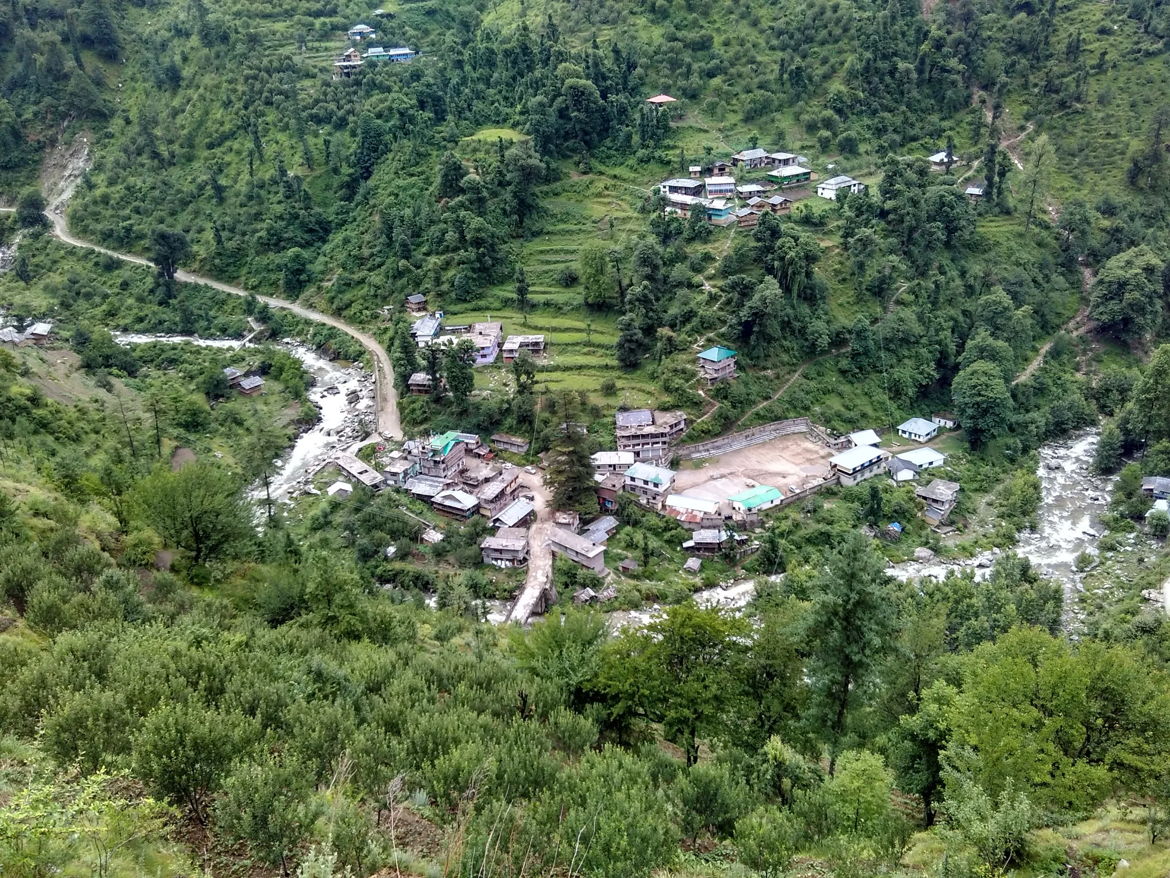 Bathad village, the starting point of the Bashleo Pass trek, seen from above: houses and terraced fields where the Palachan stream meets the road, with forested slopes all round