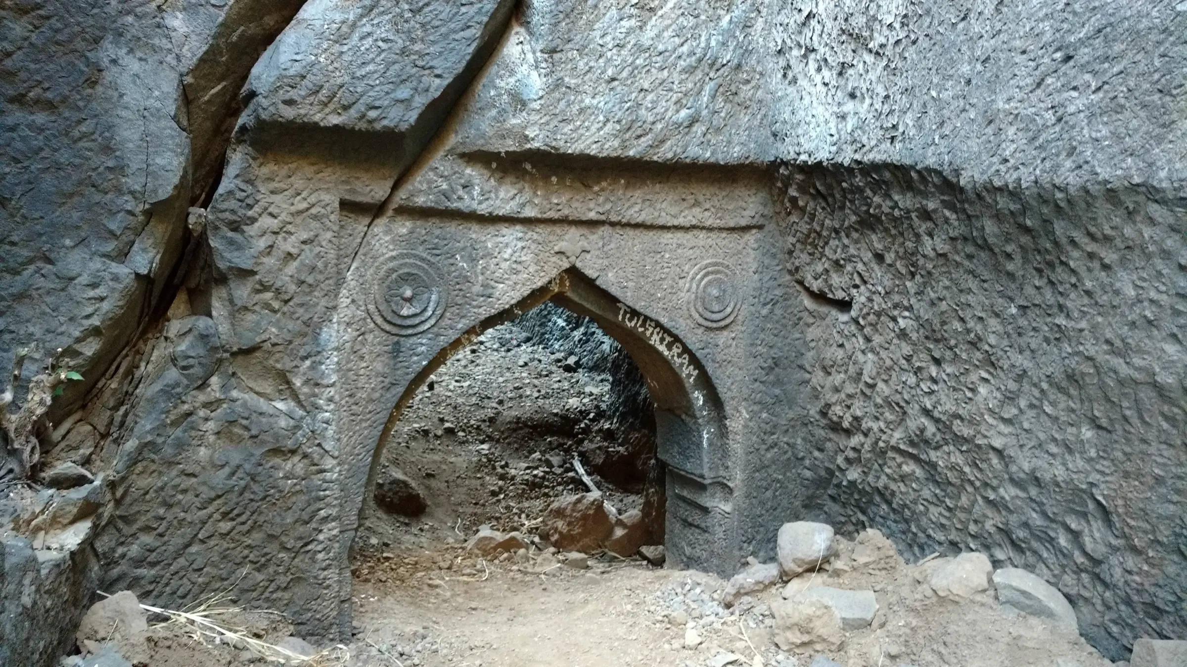 Rock-cut arched main gate of Bhaskargad with carved rosettes, half-filled with stones