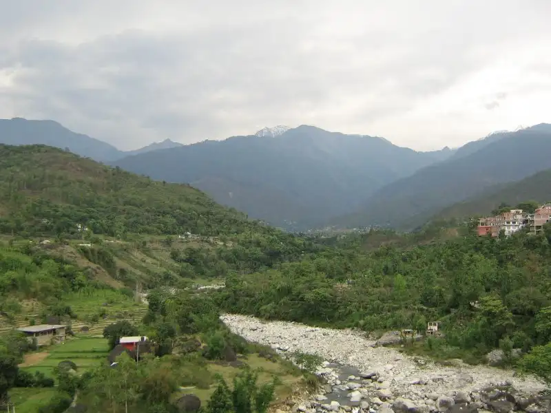 The rocky Binwa river bed and forested hills near Baijnath, the valley the trek climbs (not the trail itself)