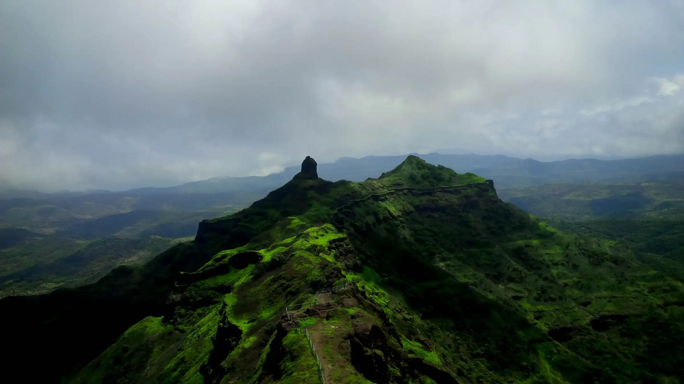 Green Budhla Machi spur of Torna Fort with its rock pinnacle, under grey monsoon clouds