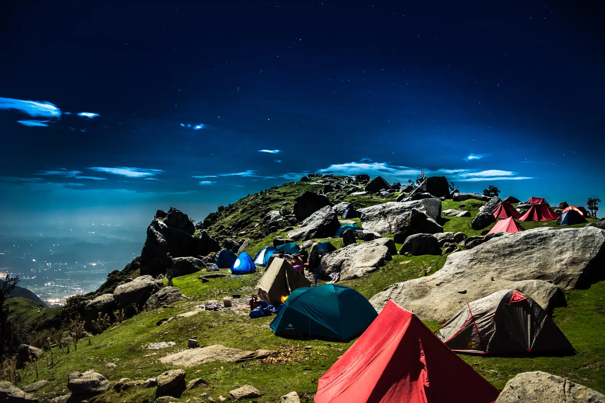 Tents pitched among boulders on the Triund hill campsite at night