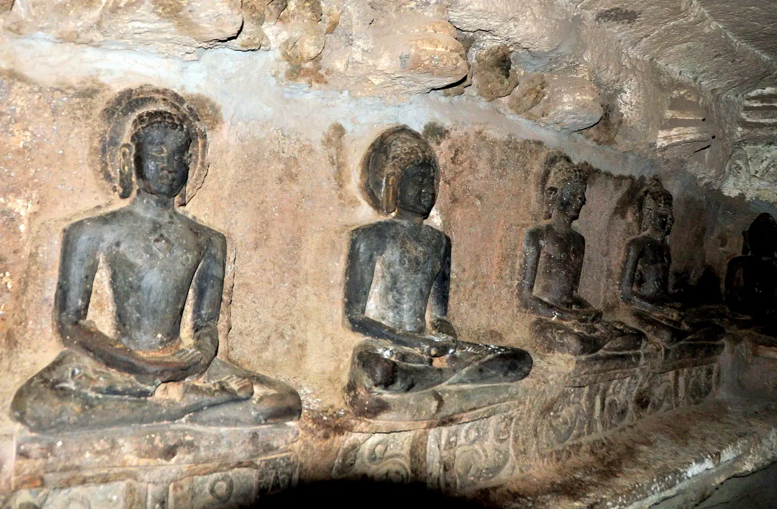 Row of seated Tirthankara images carved in a rock-cut Jain cave at Mangi Tungi