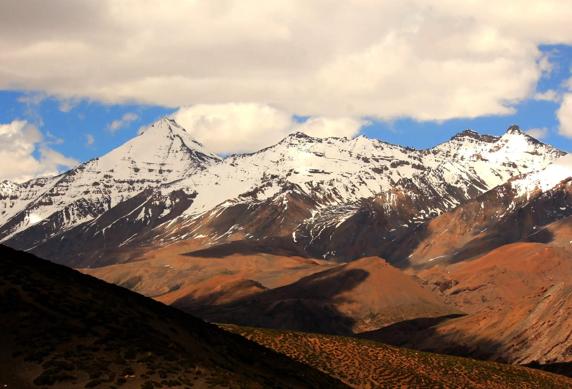 Snow-capped Chau Chau Kang Nilda peak above the brown hills near Demul village, close to the Balang Ri trek, in Spiti