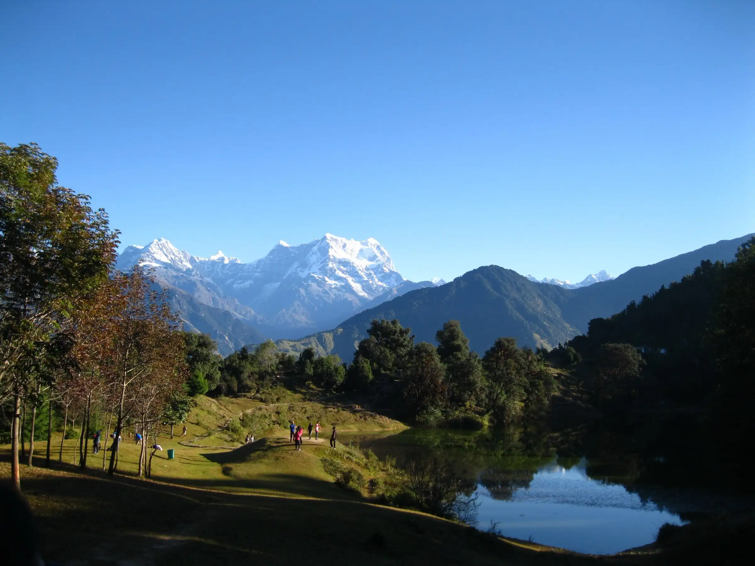 Snow-covered Chaukhamba massif above forested ridges and the Deoriatal lake meadow, the first camp on the Bisurital trek