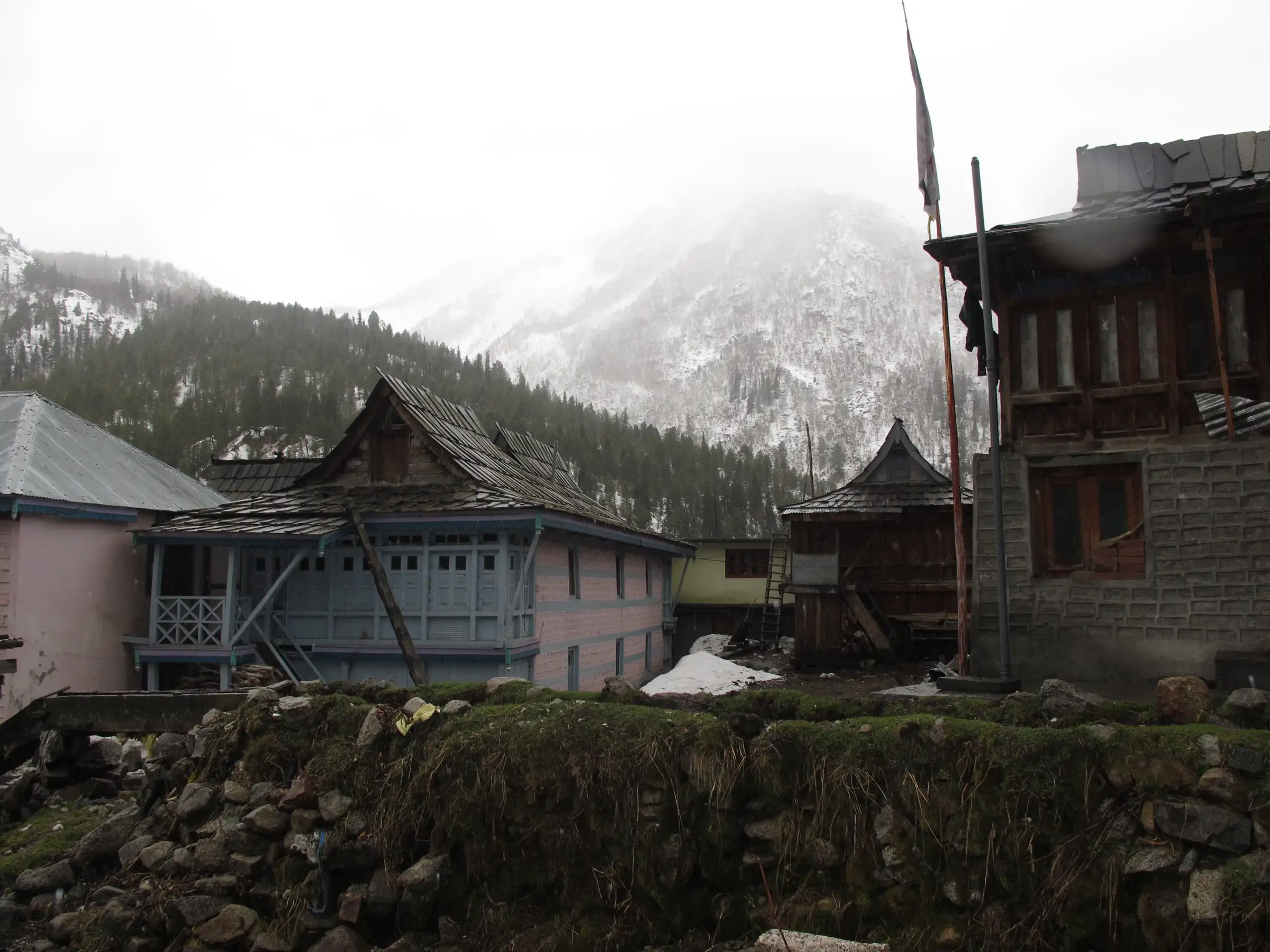 Wooden Kinnauri houses in Chitkul village under falling snow in April, the end point of the trek