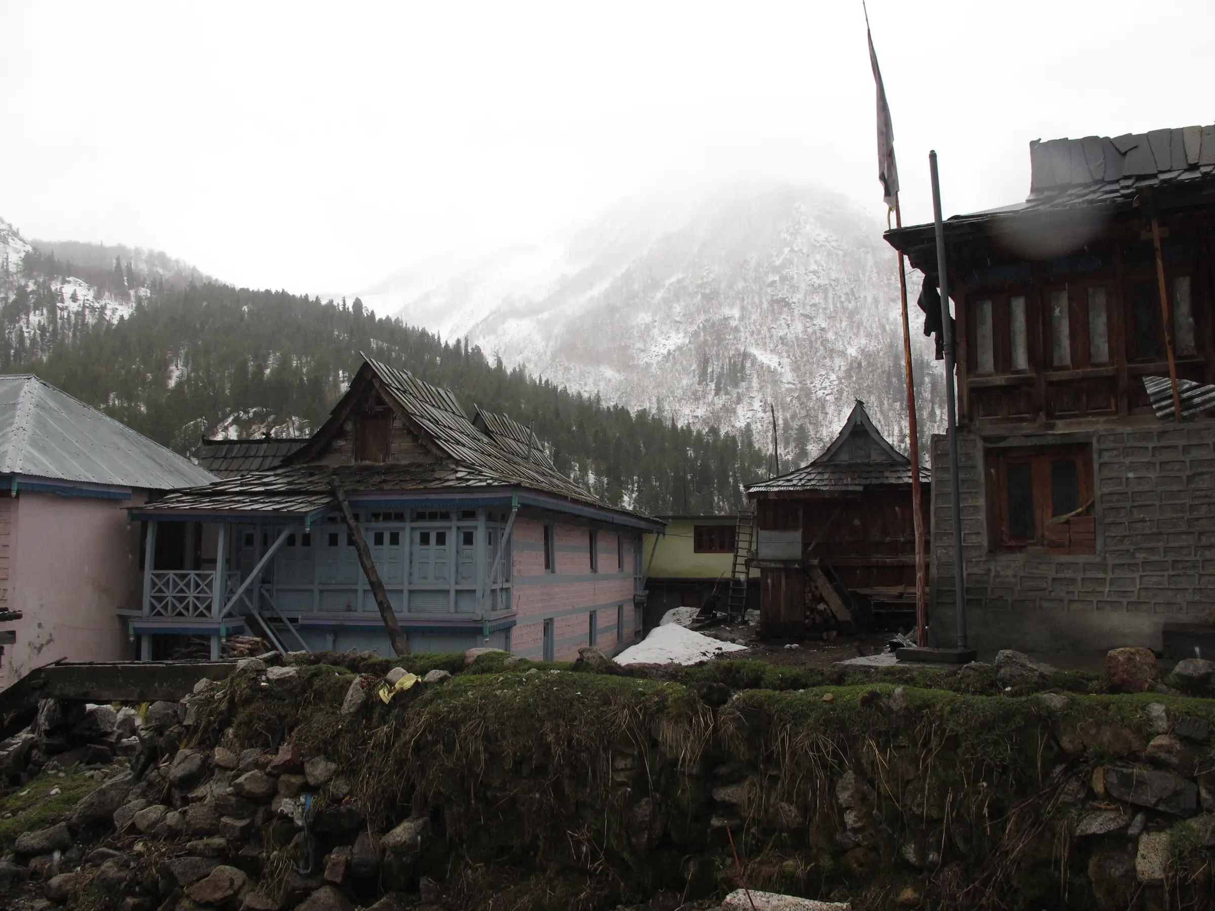 Wooden Kinnauri houses in Chitkul village under falling snow in April, the end point of the trek