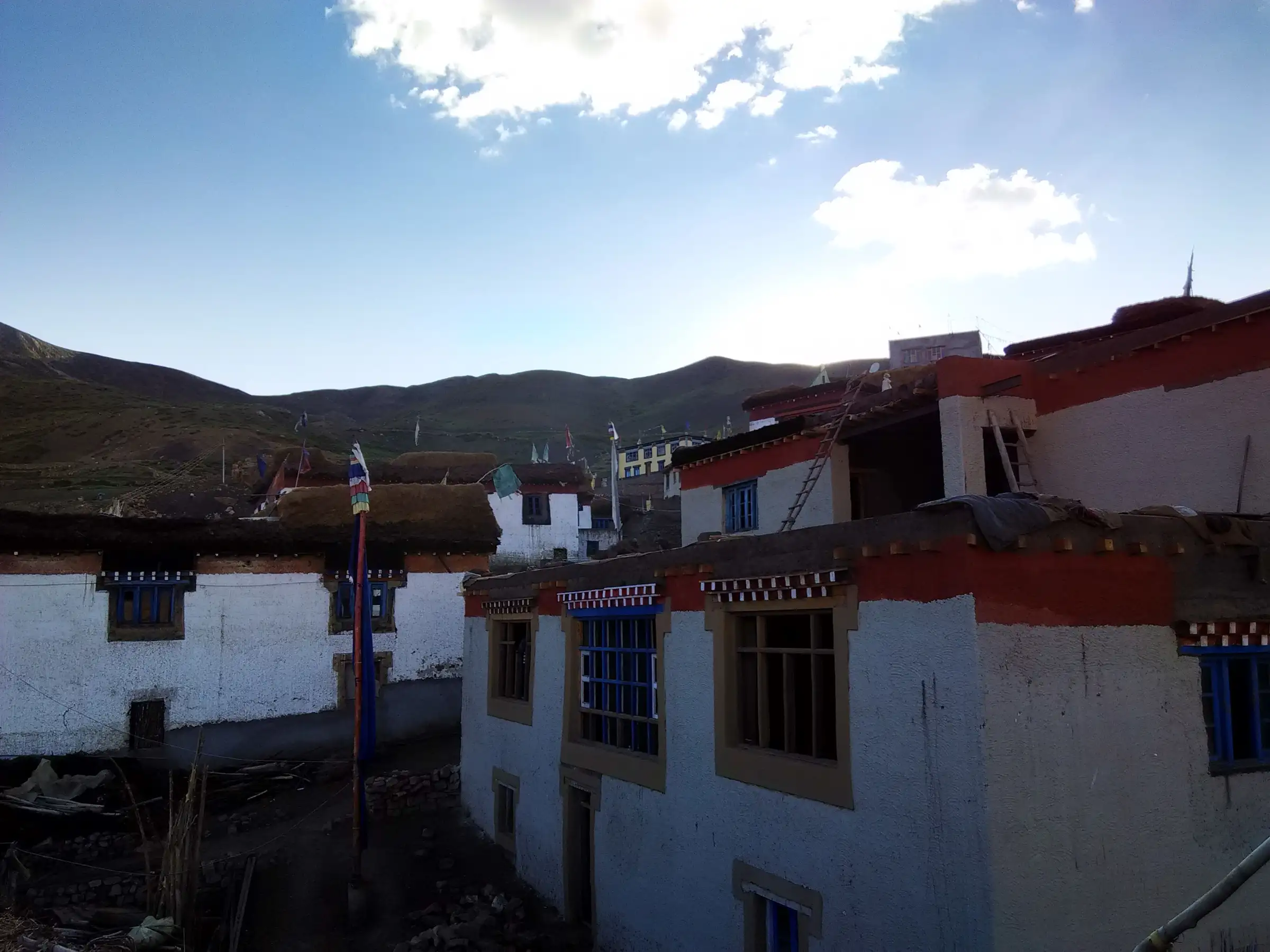 Whitewashed Spitian houses with red-trimmed roofs and a prayer-flag pole in Demul village, an overnight stop on the trek