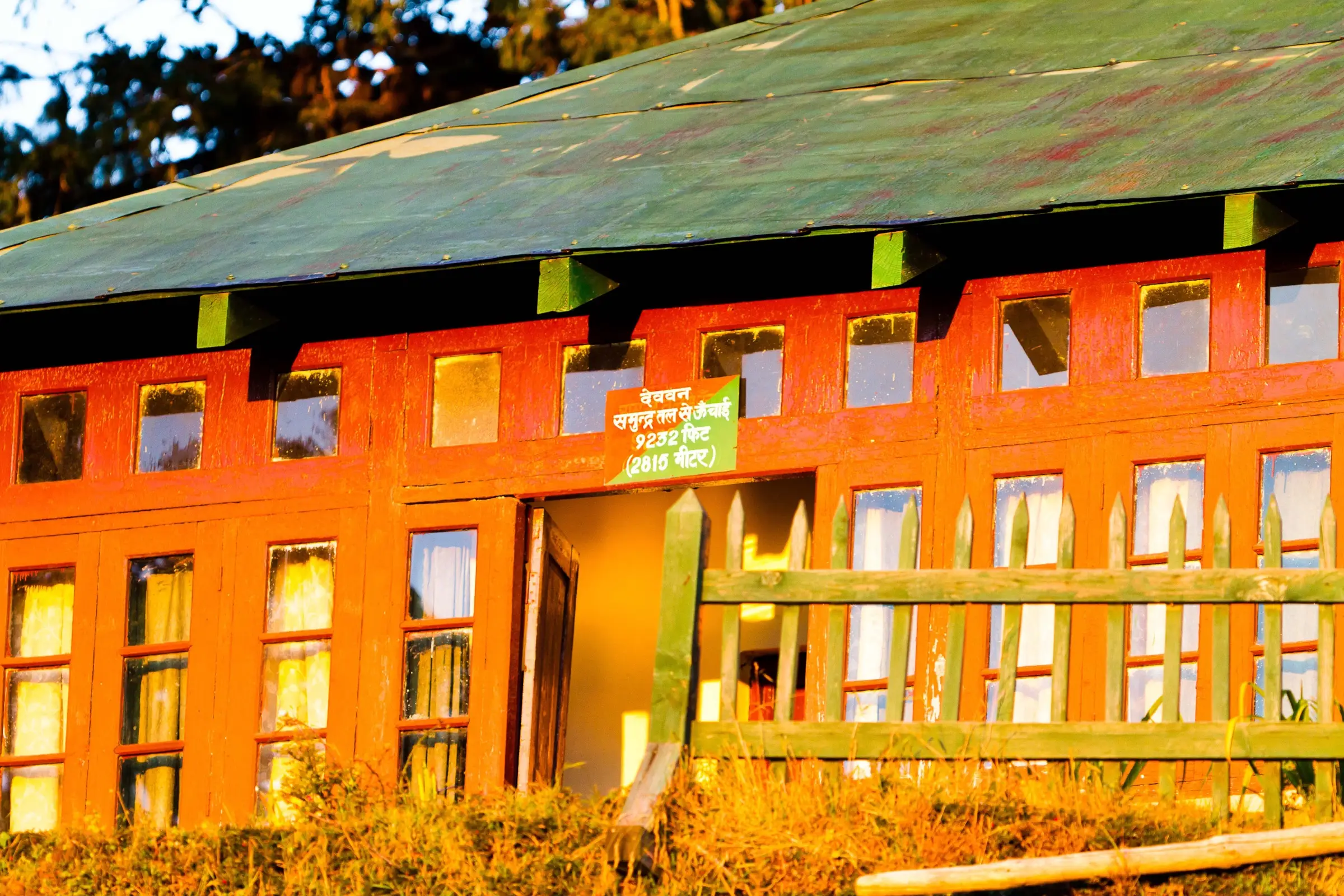 Orange wooden Forest Rest House at Deoban in evening light, with a sign giving its height as 9,232 ft (2,815 m)