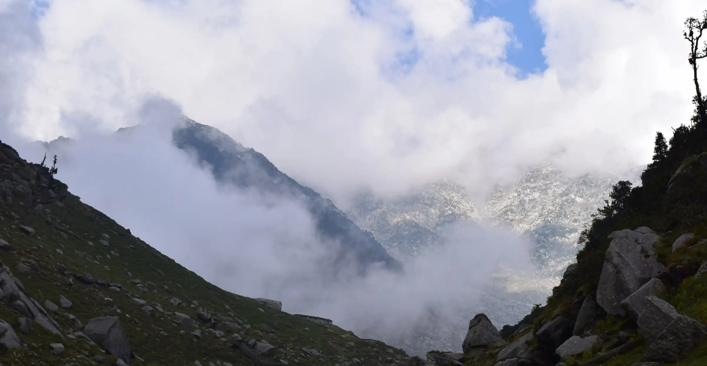 Cloud lifting off the snowy Dhauladhar range seen from the valley beyond Kareri Lake, on the way towards Minkiani Pass