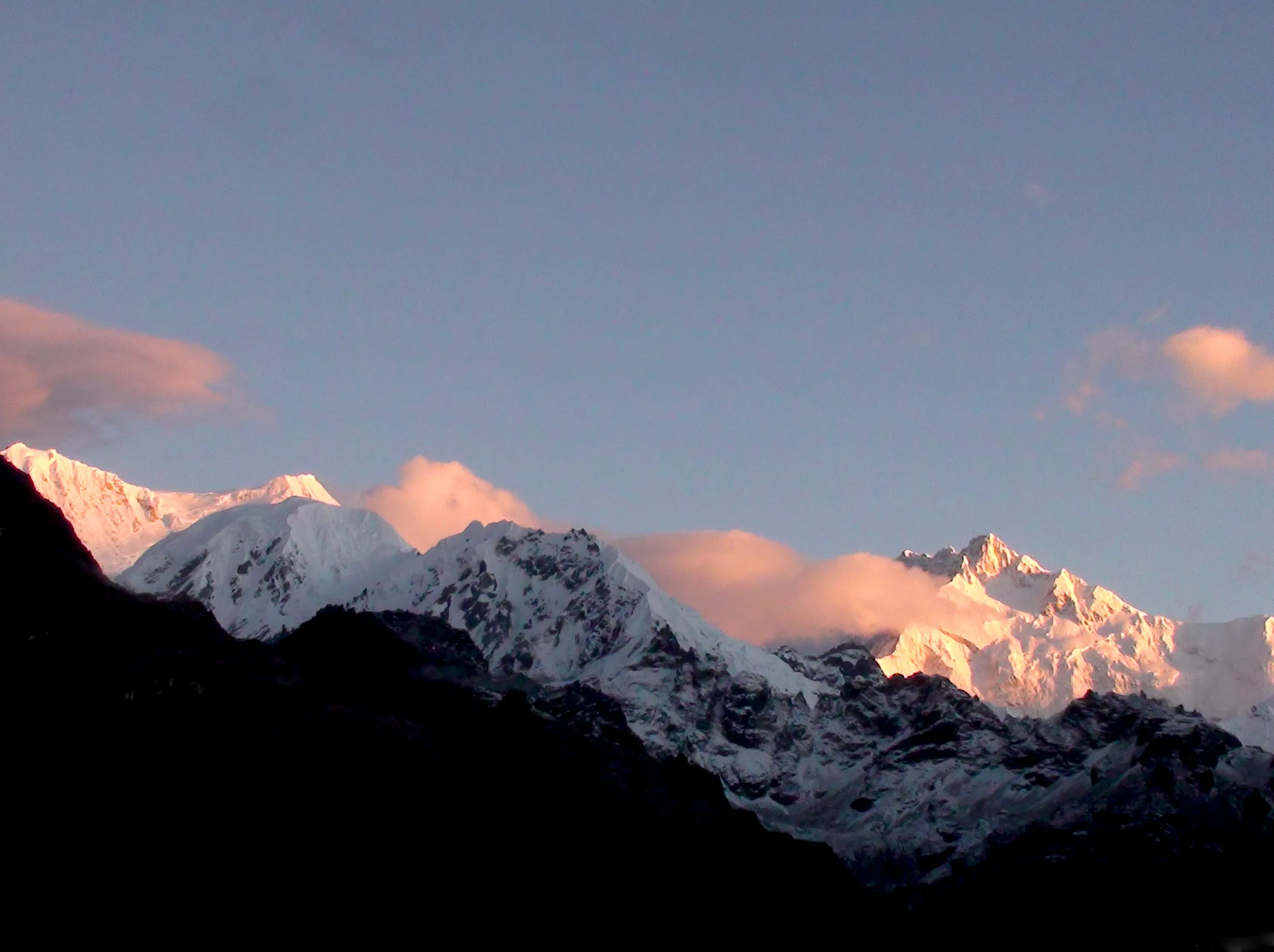 Sunrise light on Kabru and Kanchenjunga seen from the Dzongri viewpoint, with dark ridges in the foreground