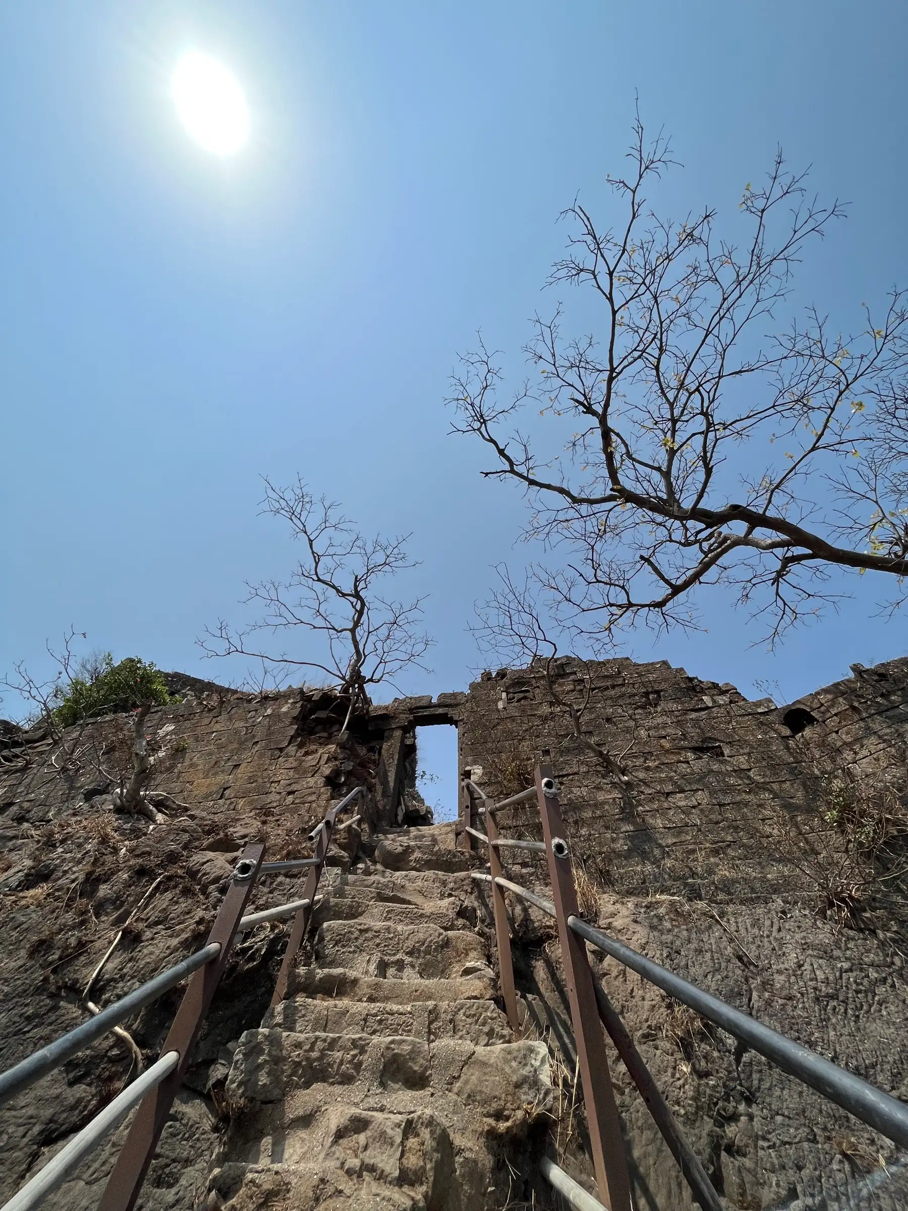 Stone steps with metal railings leading up to the narrow gateway in the Karnala Fort wall