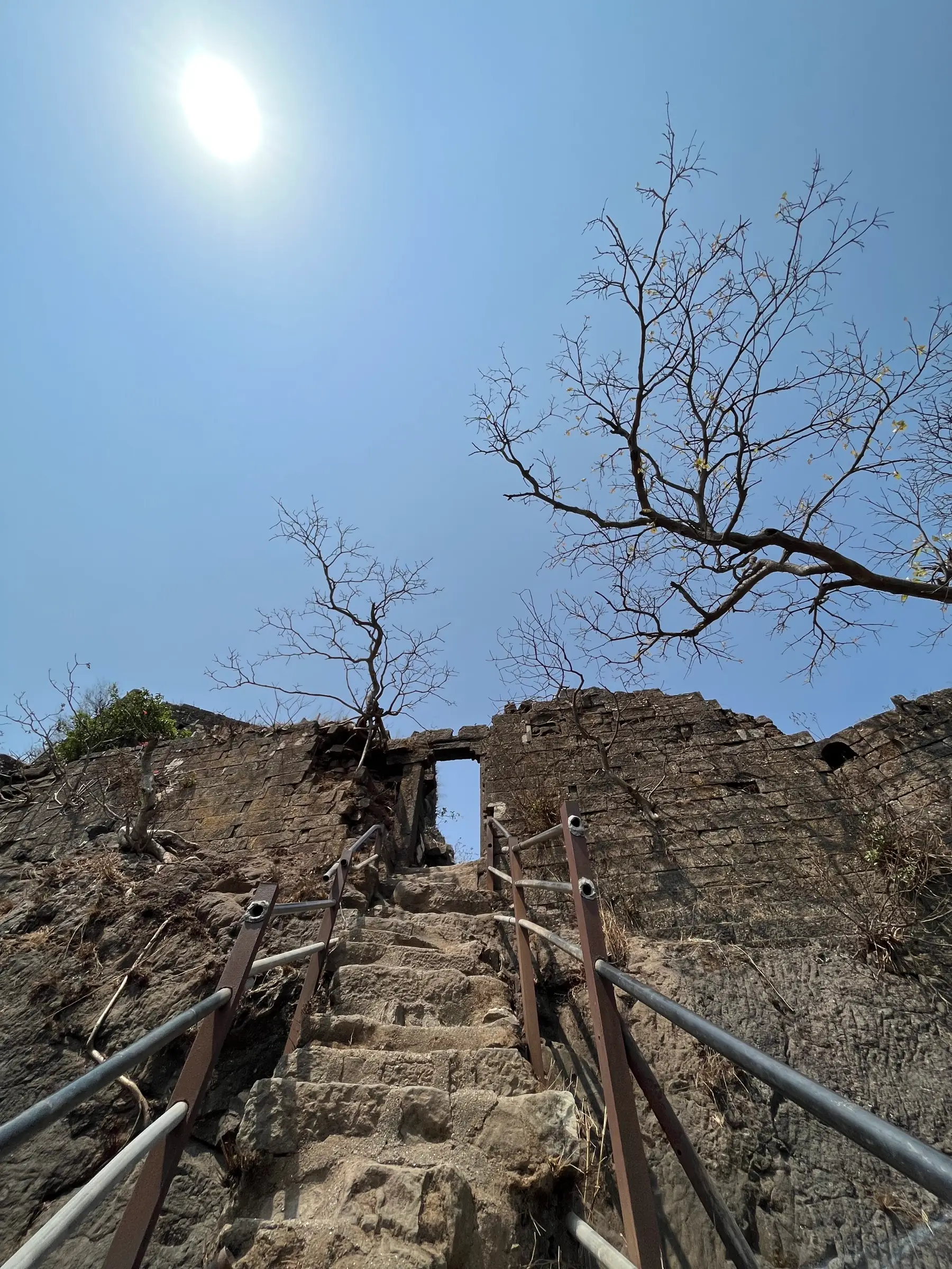 Stone steps with metal railings leading up to the narrow gateway in the Karnala Fort wall