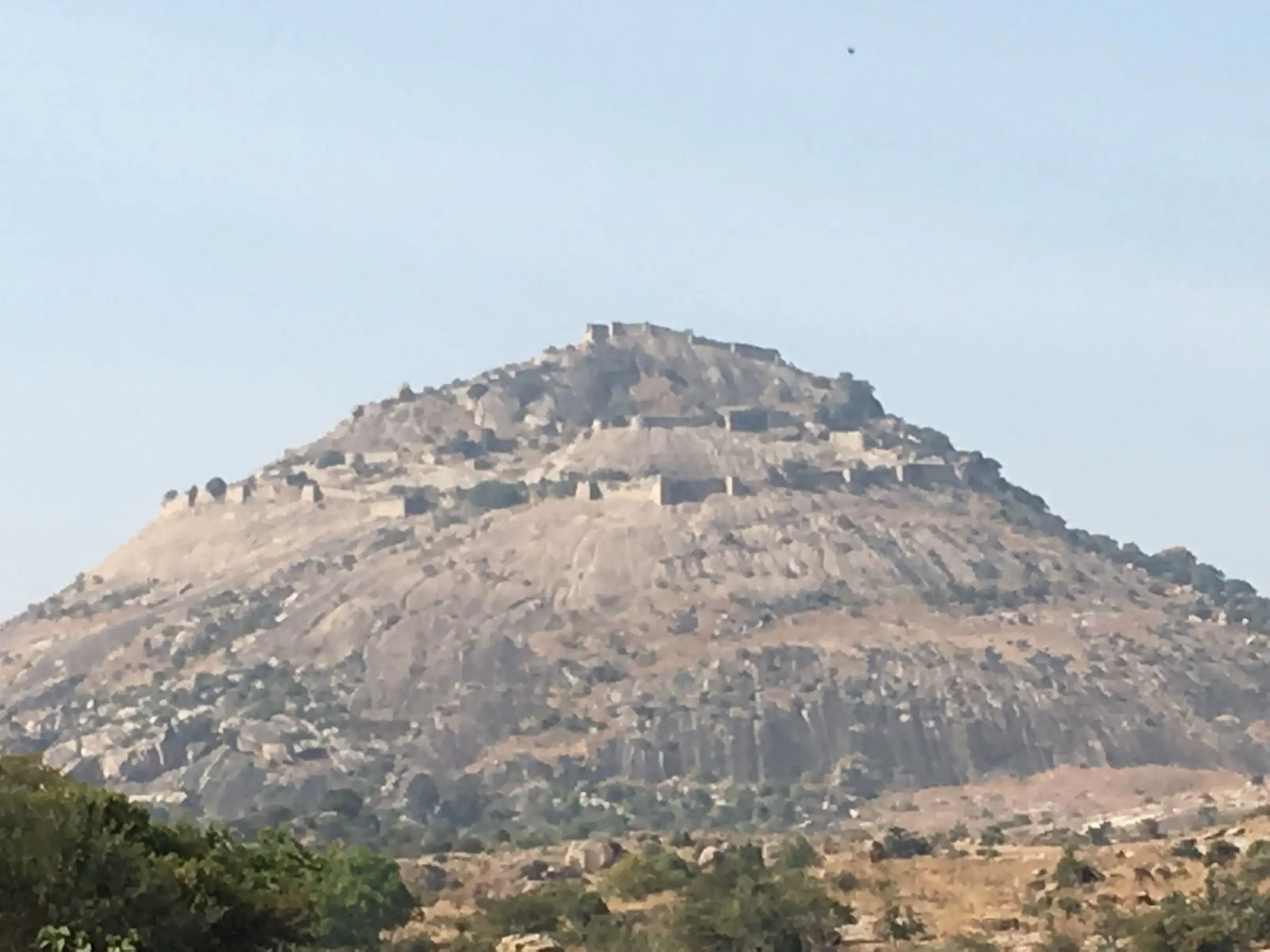 Channarayana Durga hill seen from the plains, a bare granite dome ringed by layers of fort walls up to the summit