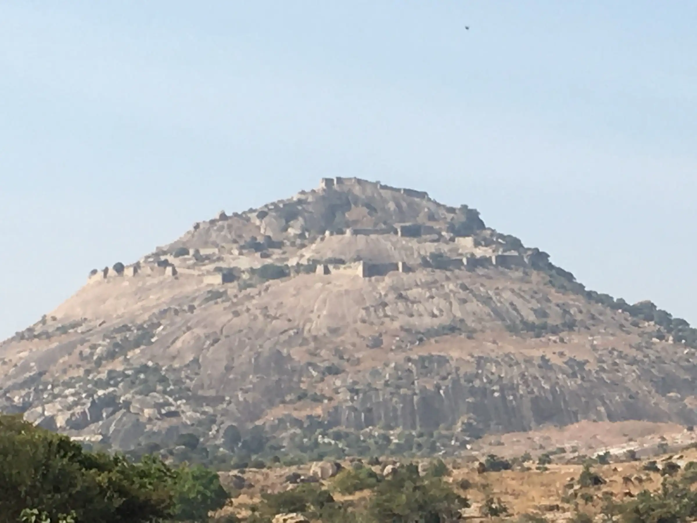 Channarayana Durga hill seen from the plains, a bare granite dome ringed by layers of fort walls up to the summit