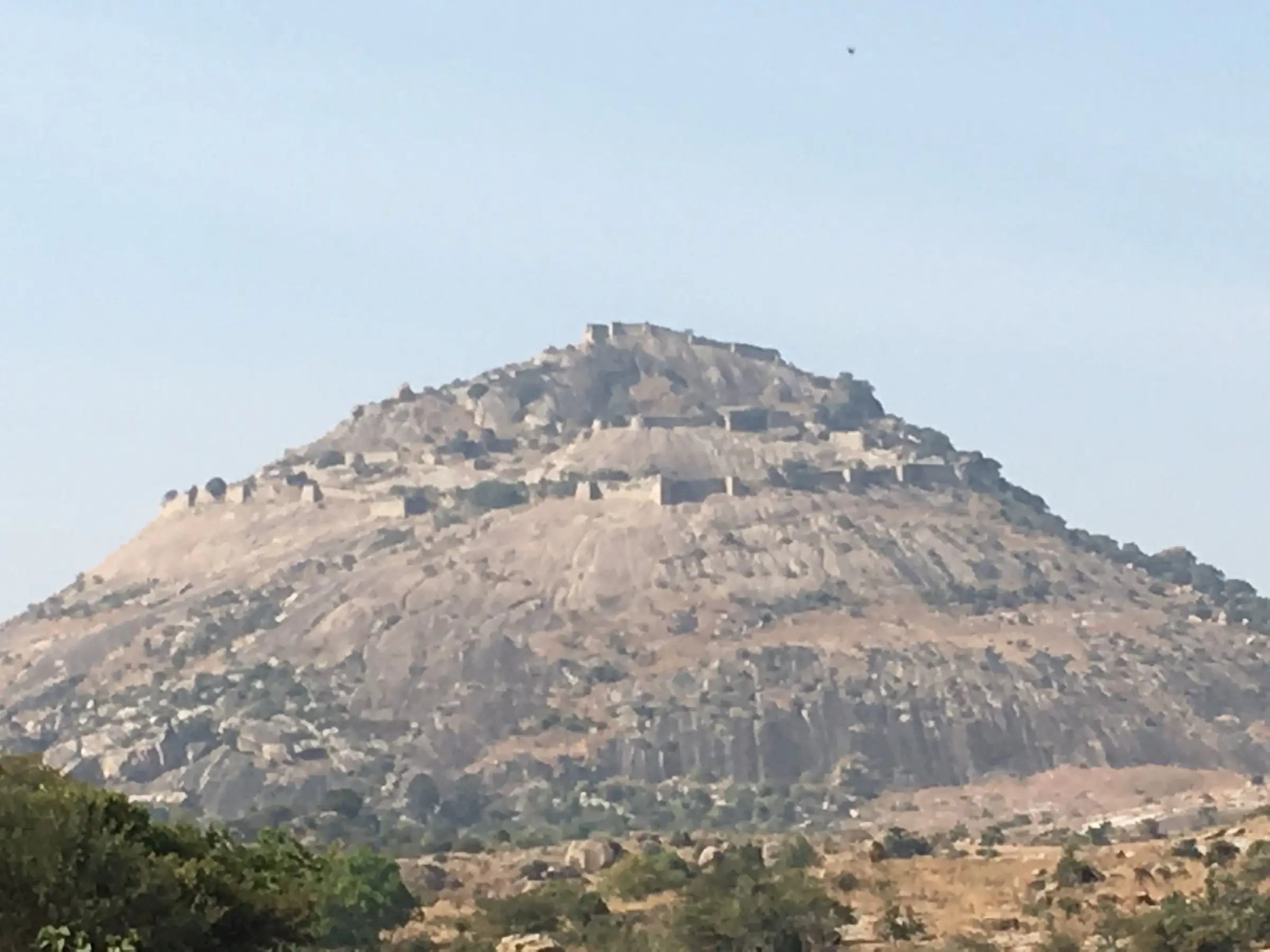 Channarayana Durga hill seen from the plains, a bare granite dome ringed by layers of fort walls up to the summit
