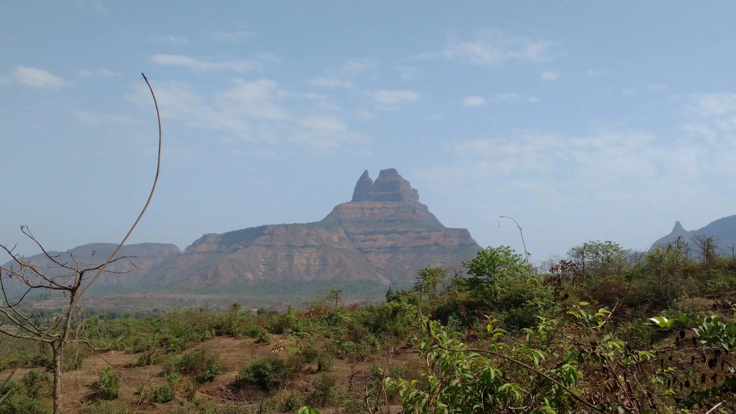 Malanggad seen from the dry plains, with the twin rock pinnacles of the Balekilla rising above a long cliff band