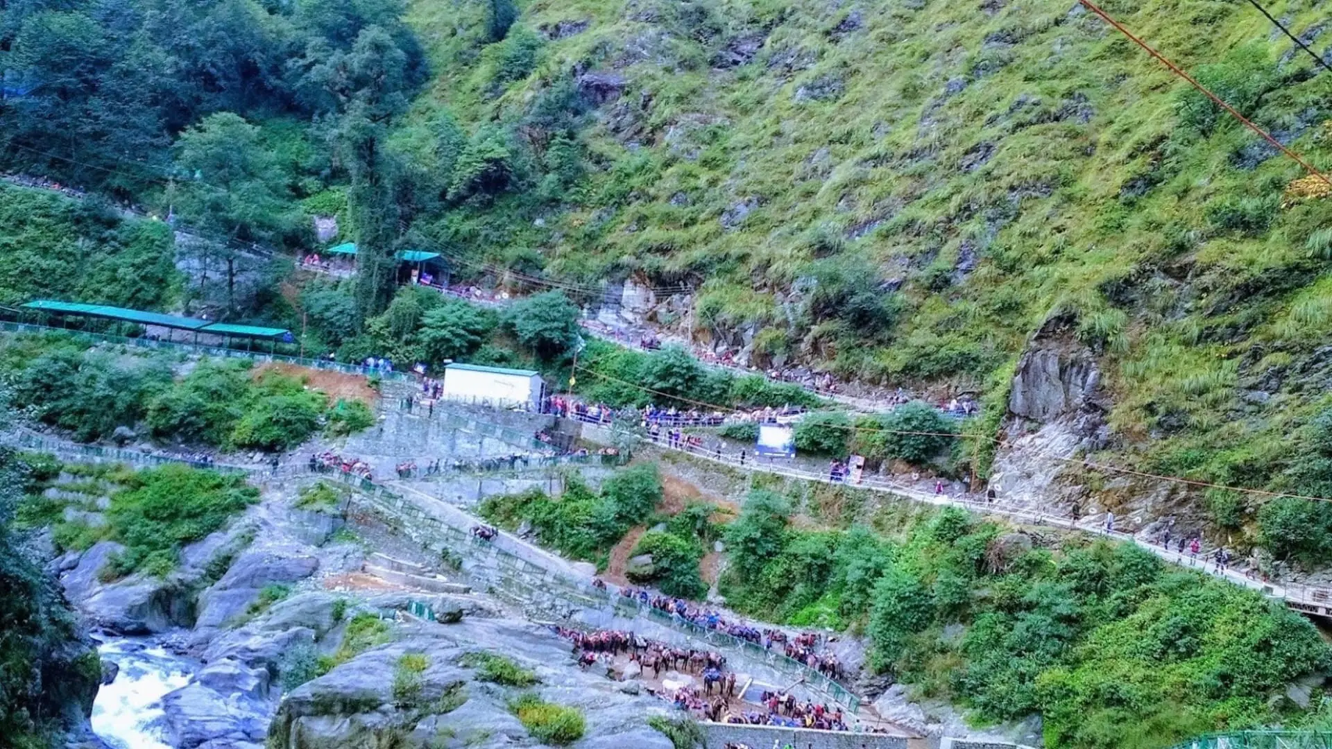 Pilgrims and ponies on the paved Kedarnath path leaving Gaurikund along a green, steep-sided valley