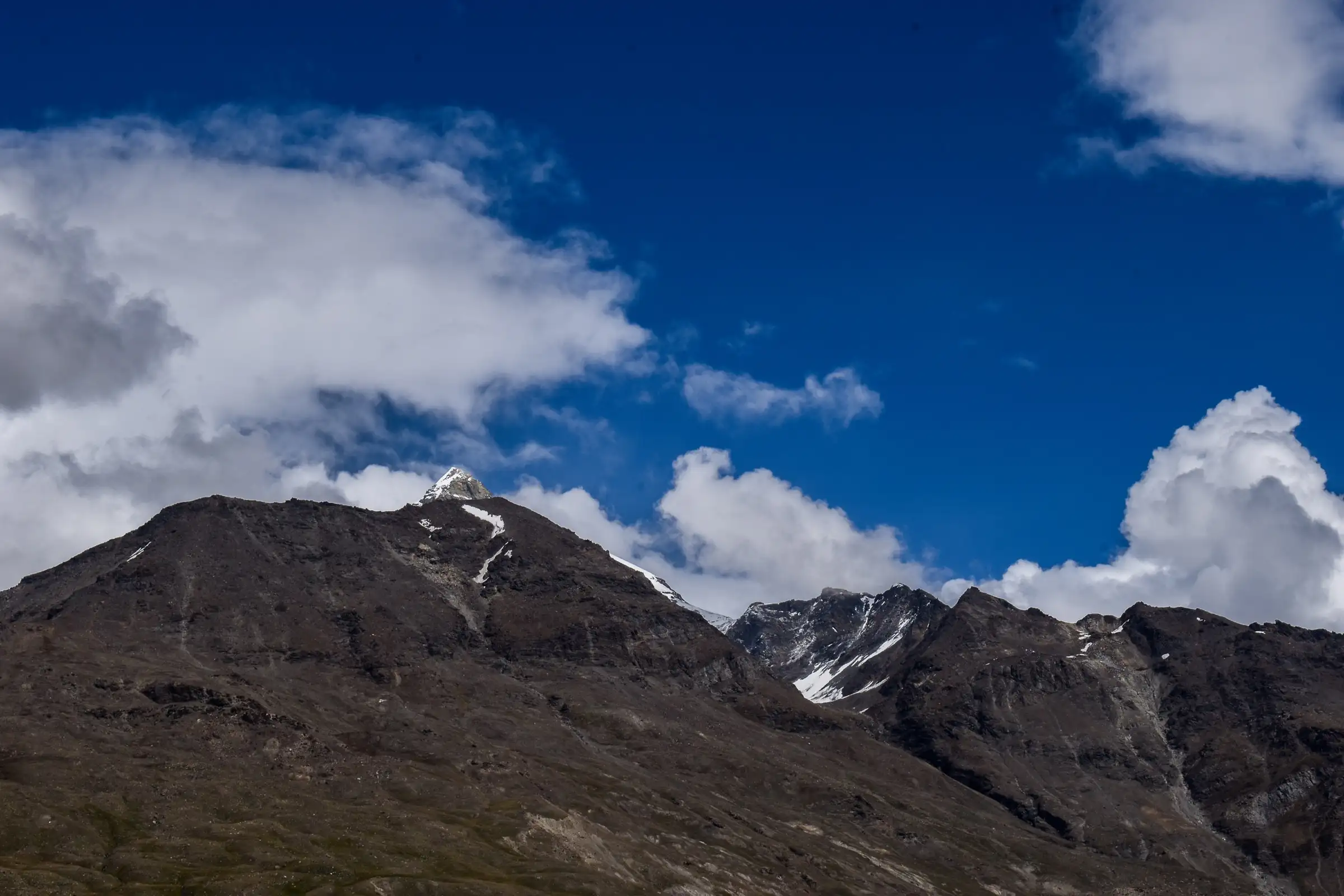 Snow-tipped Ghepan Goh peak above dark rocky ridges, seen from near Sissu at the start of the trek