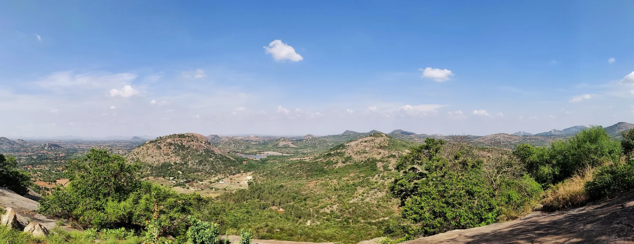 Panorama of scrub-covered granite hills and a small lake from Avalabetta, a neighbouring hill seen from the Varlakonda summit. This is the surrounding area, not the Varlakonda trail itself