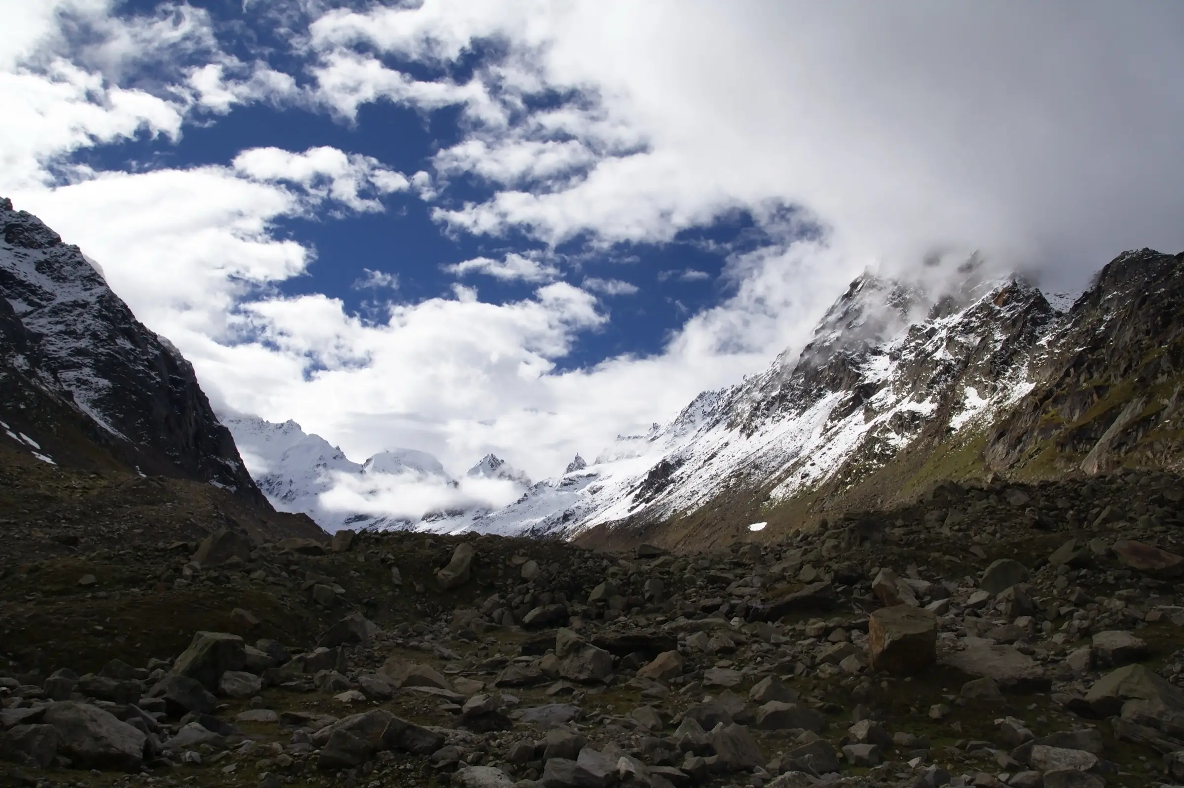 Rocky moraine and snow peaks under cloud at Hampta Pass, Himachal Pradesh