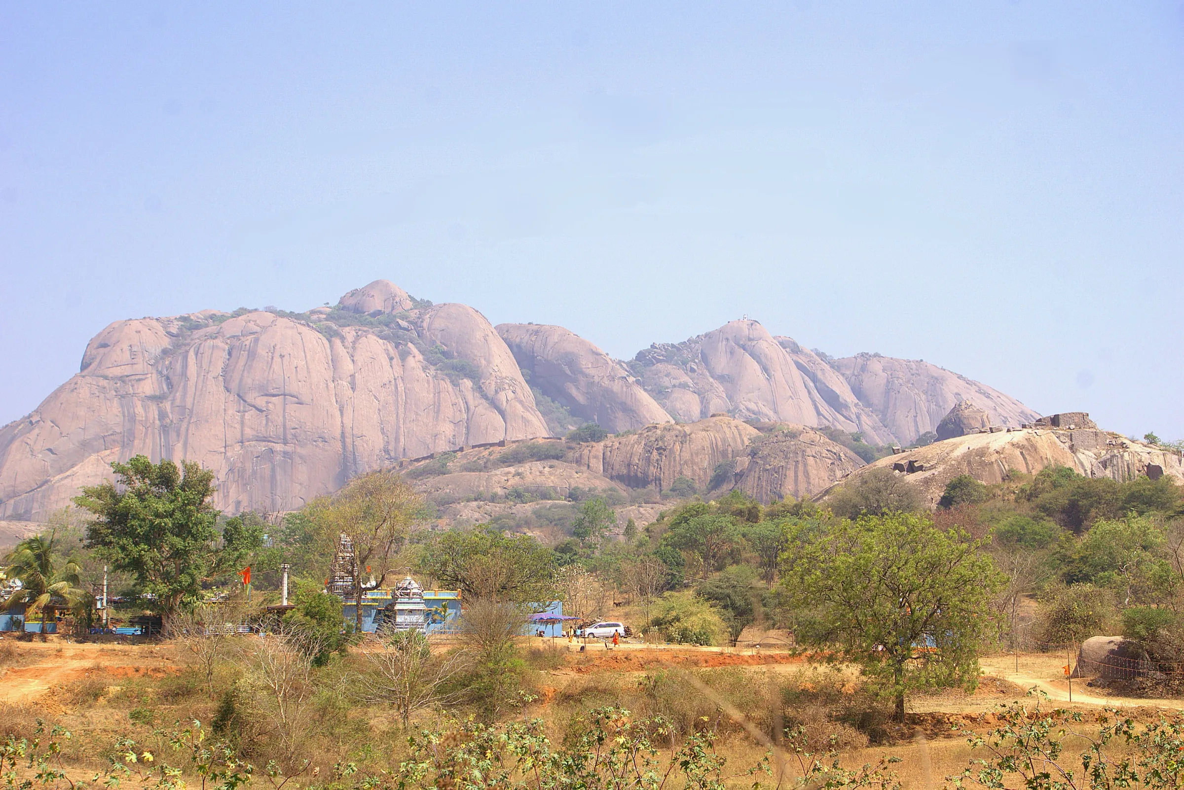 Savandurga's pink granite domes and lower rocky spurs with old fort walls, seen from the south above the base temples near where the Bidirukatte trail starts (photo of the neighbouring hill, not the Bidirukatte trail itself)