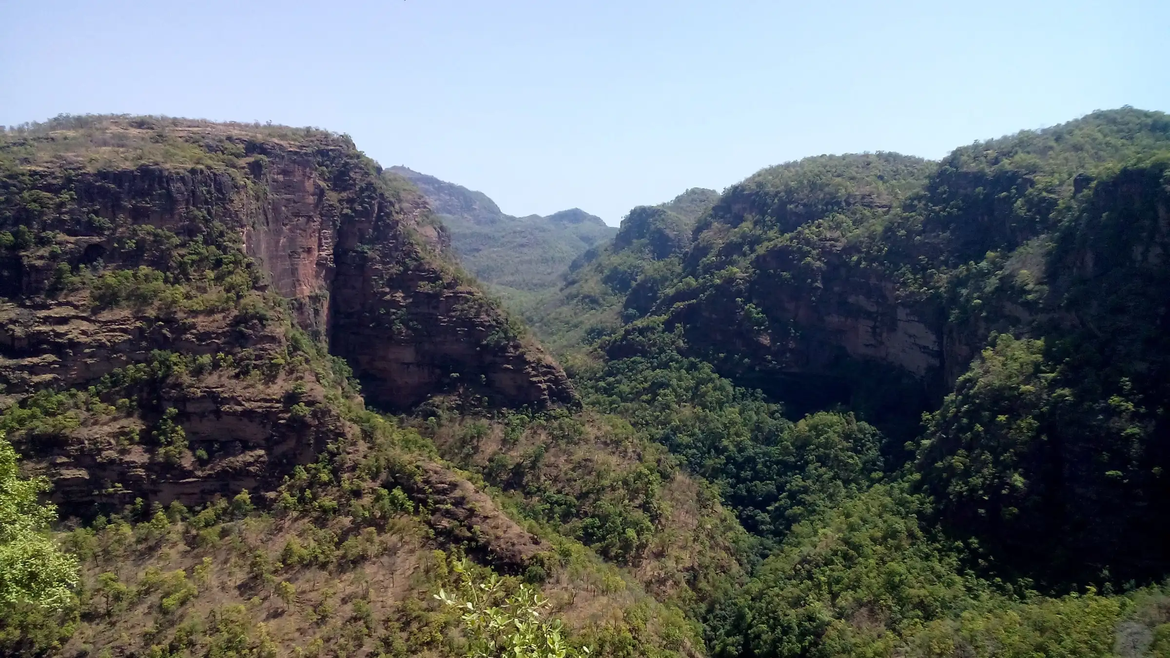 Forest-covered sandstone cliffs and a deep green valley on the far side of the Silver Fall gorge
