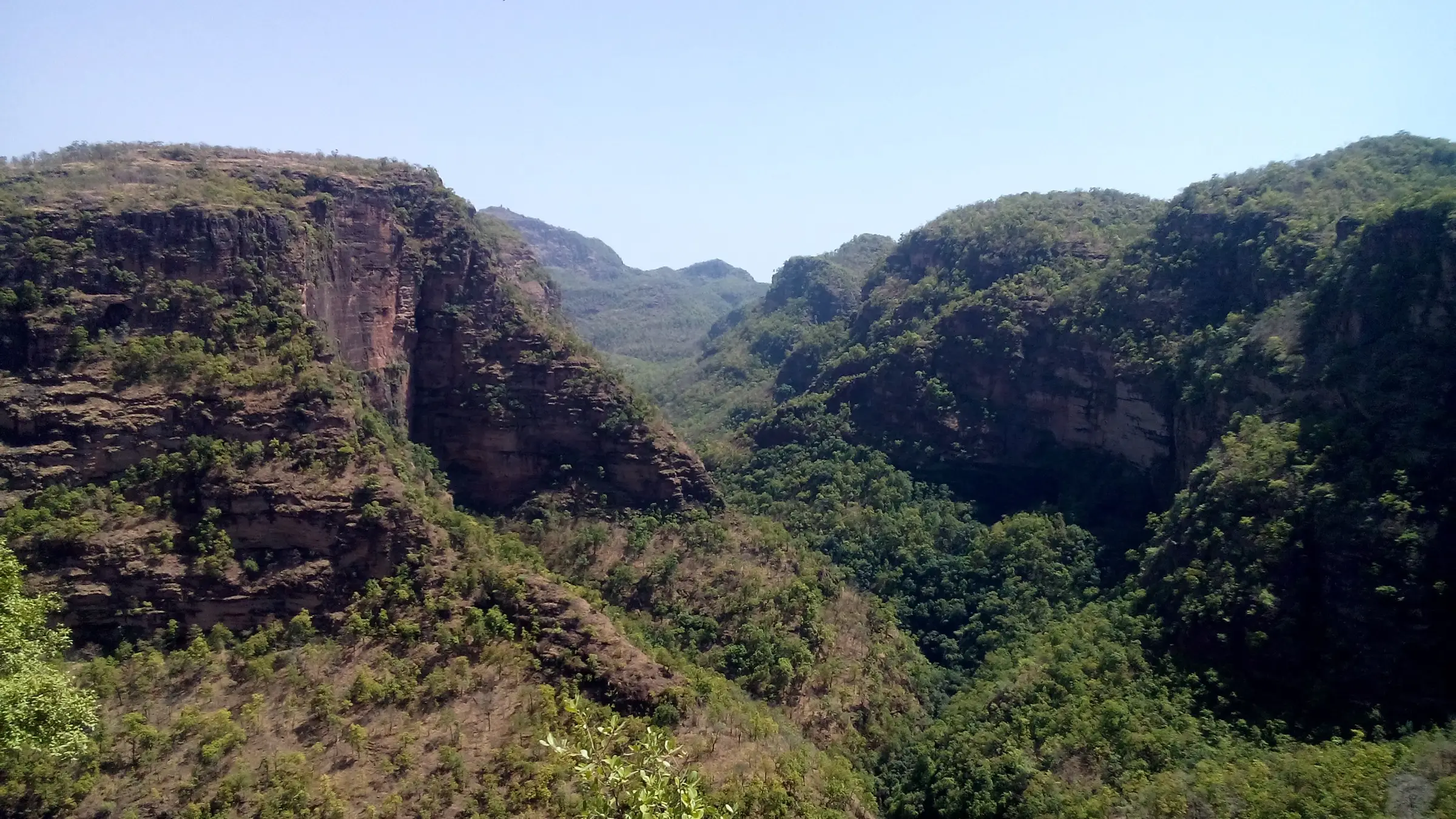 Forest-covered sandstone cliffs and a deep green valley on the far side of the Silver Fall gorge