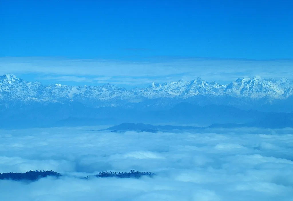 Snow-capped Kumaon Himalaya peaks rising above a sea of cloud, seen from Binsar