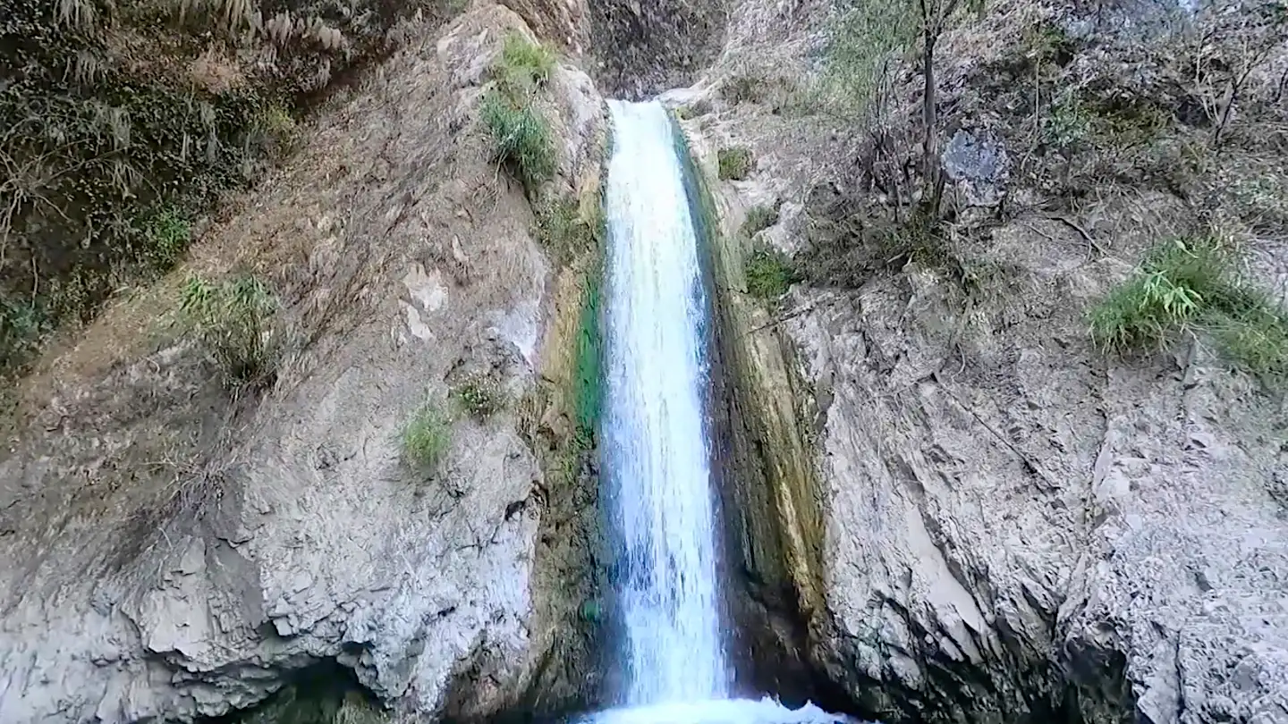 Jharipani waterfall pouring down a narrow cleft in grey rock, a short detour from the midpoint of the Kipling Trail
