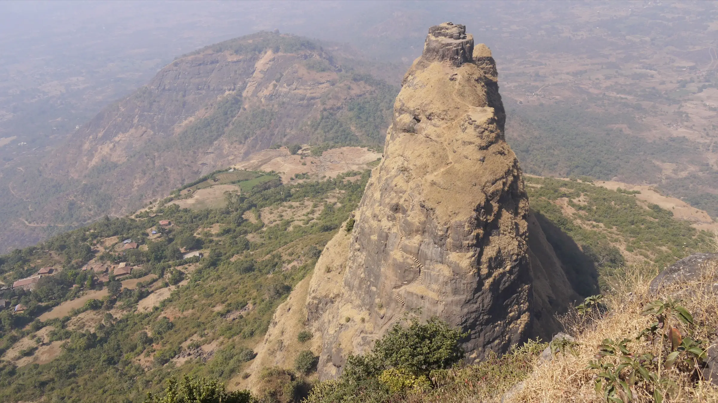 Kalavantin Durg pinnacle with its rock-cut staircase, seen from above on Prabalgad, with Prabalmachi houses below