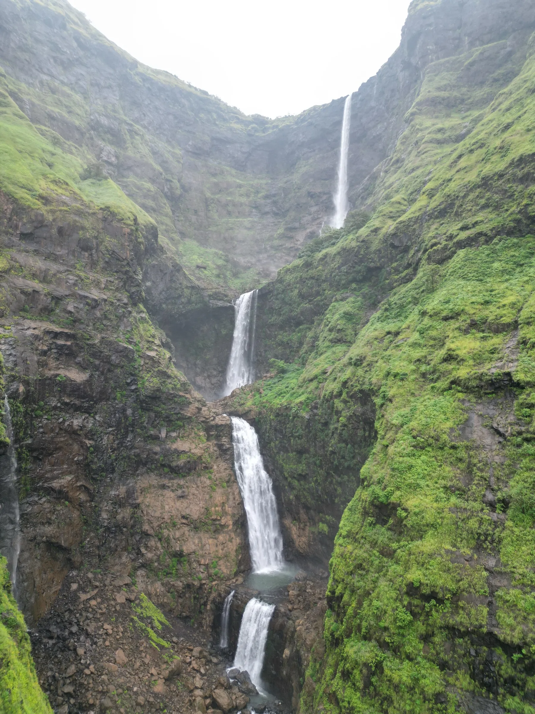 Multi-tiered Kalu Waterfall dropping through a narrow, moss-green basalt gorge in the monsoon