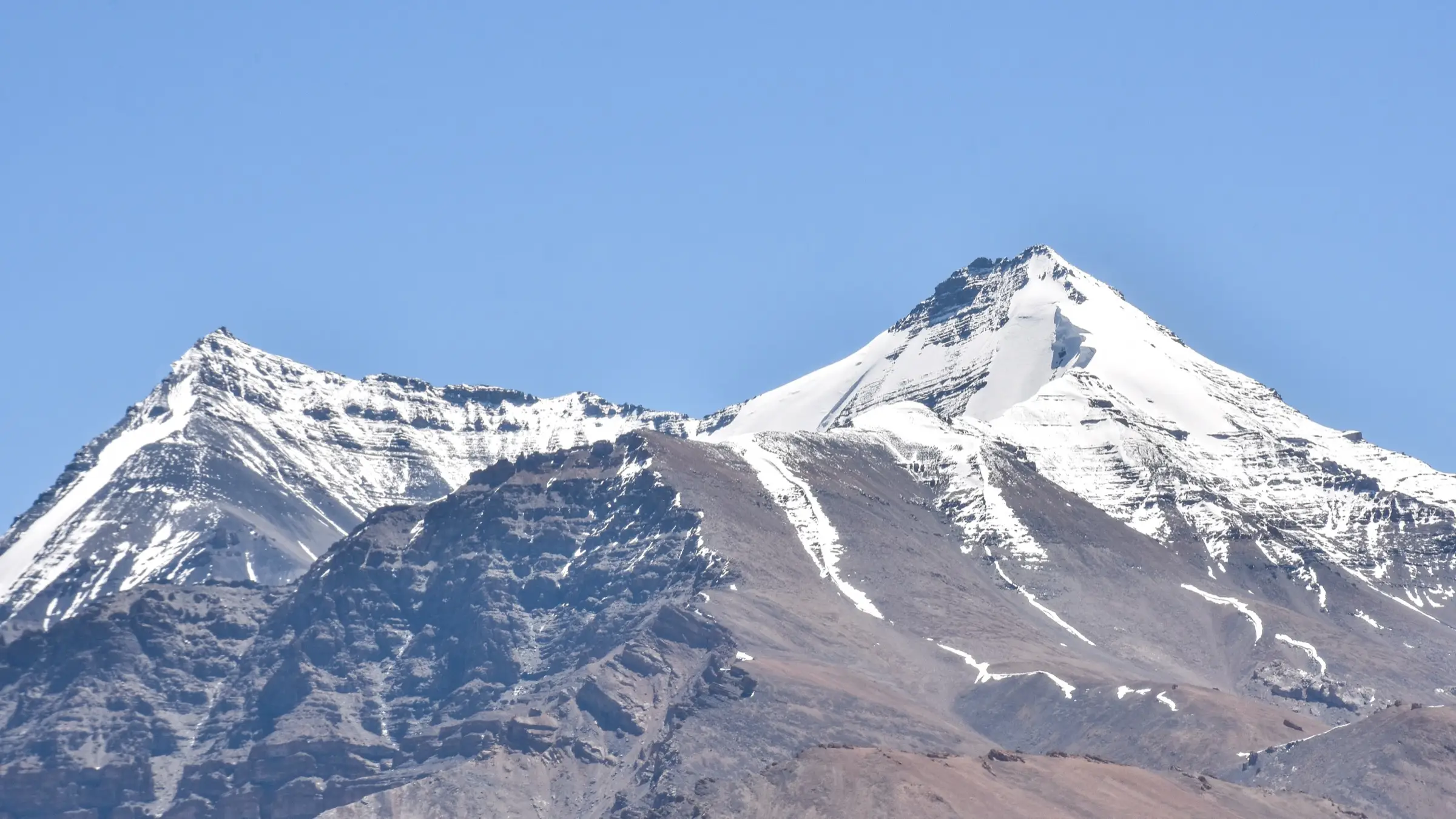 Kanamo West on the left and Kanamo Peak on the right, snow-capped above the dry slopes south of the peak in Spiti