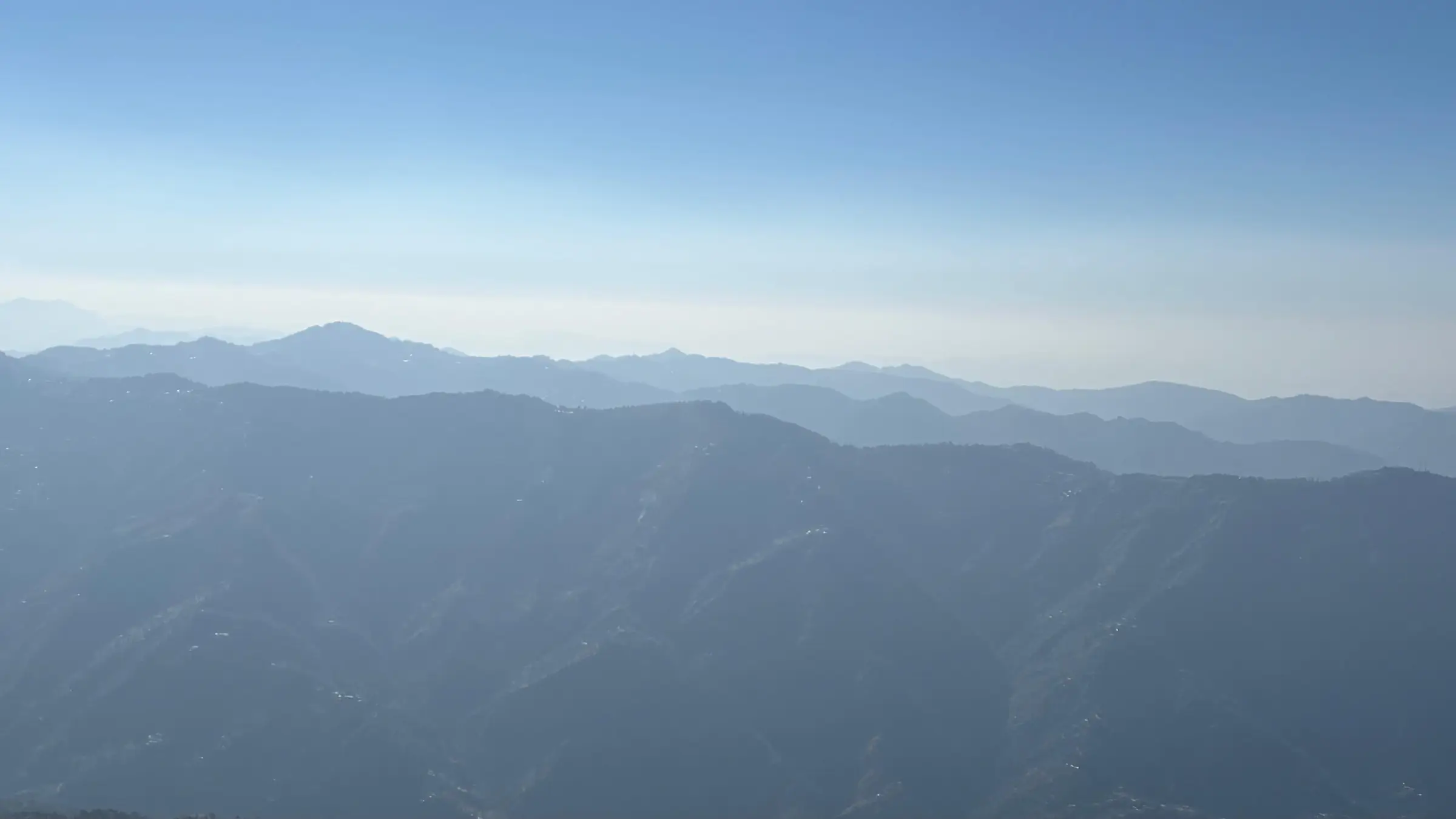 Hazy blue ridges of the Shimla and Solan hills, including Karol Tibba in the distance, seen from Shali Tibba; view of the hills around the trek, not the trail itself