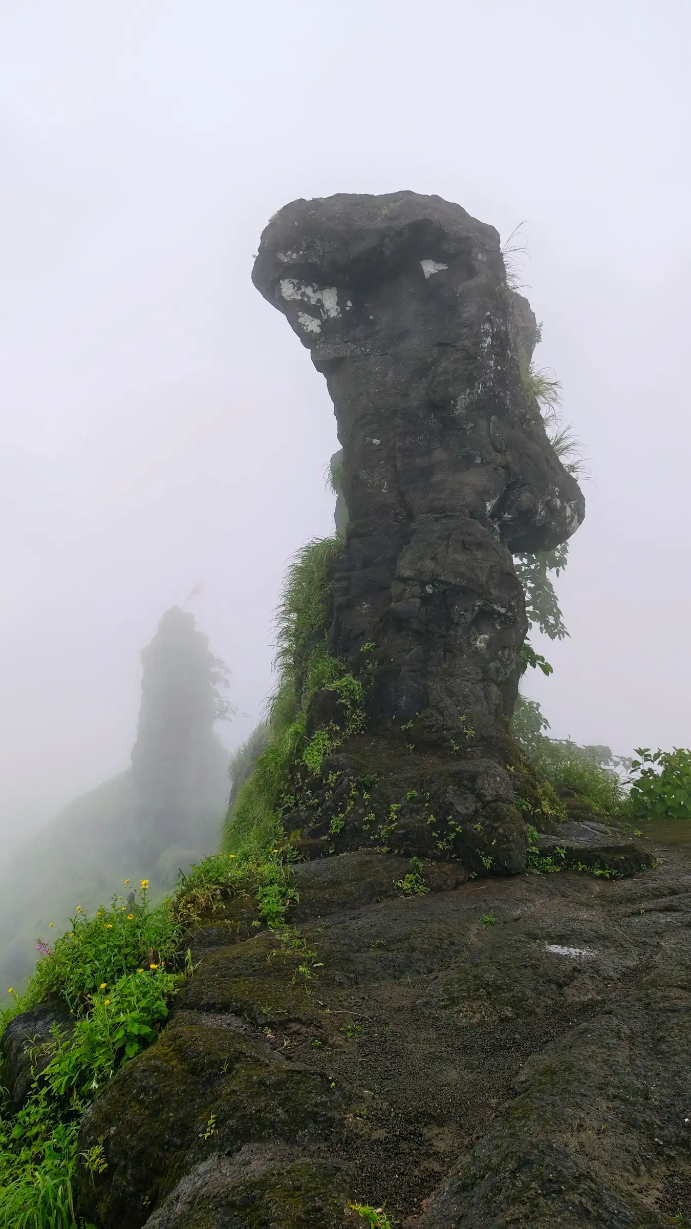 The wind-eroded man-shaped rock pinnacle on Kohoj Fort in monsoon mist