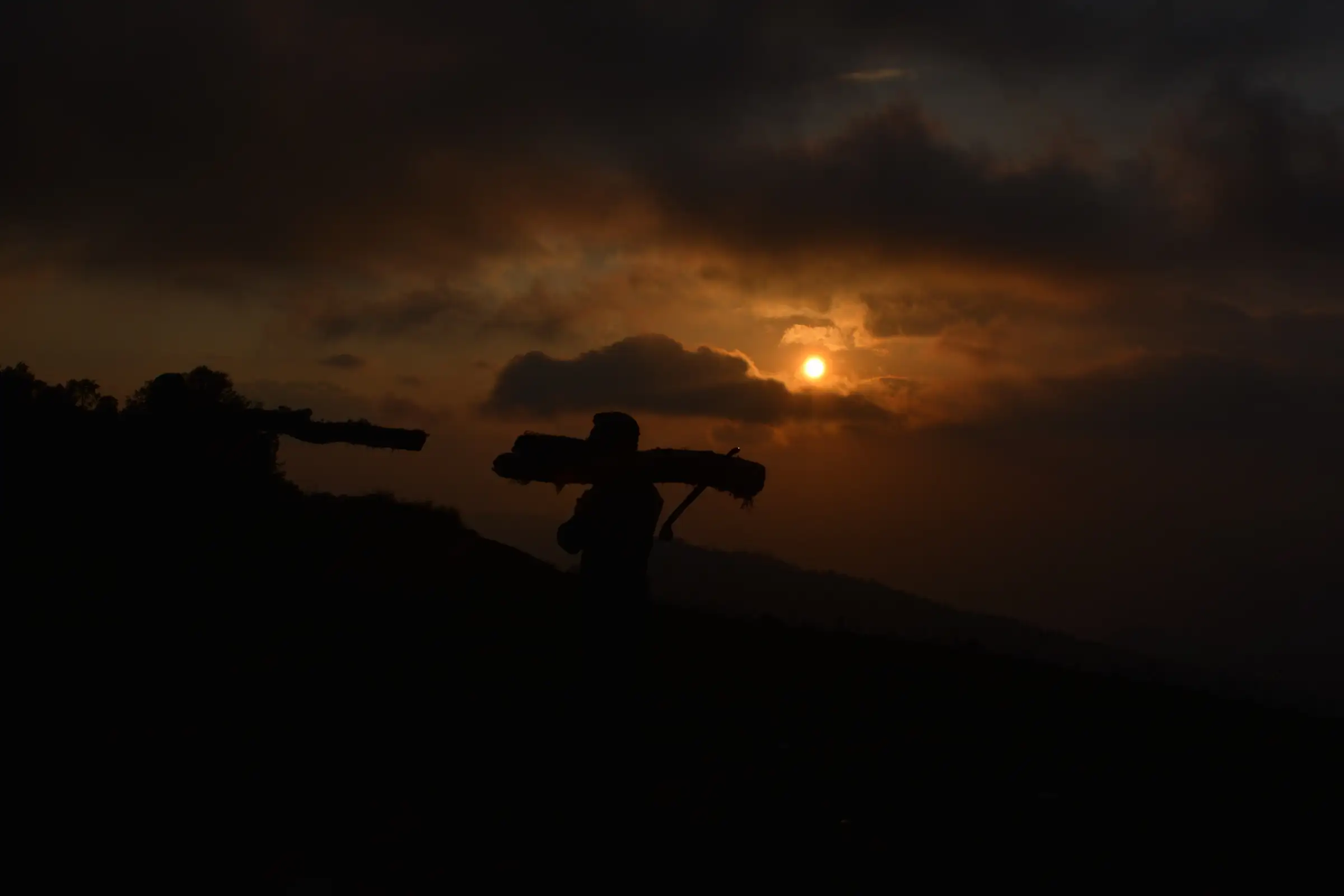 Sunset over a ridge at Kupad, Giri Ganga, with a person carrying a load silhouetted on the slope