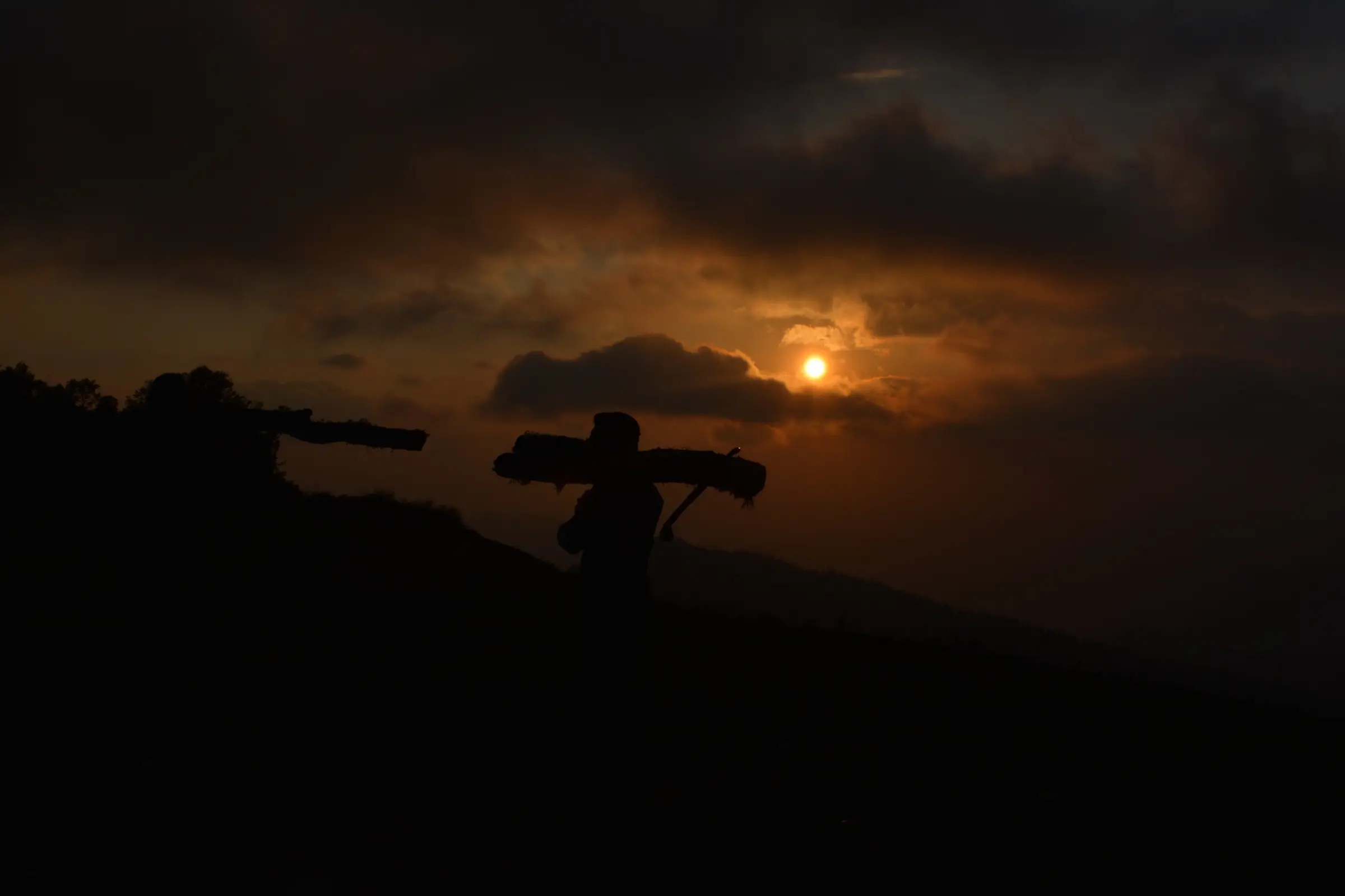 Sunset over a ridge at Kupad, Giri Ganga, with a person carrying a load silhouetted on the slope