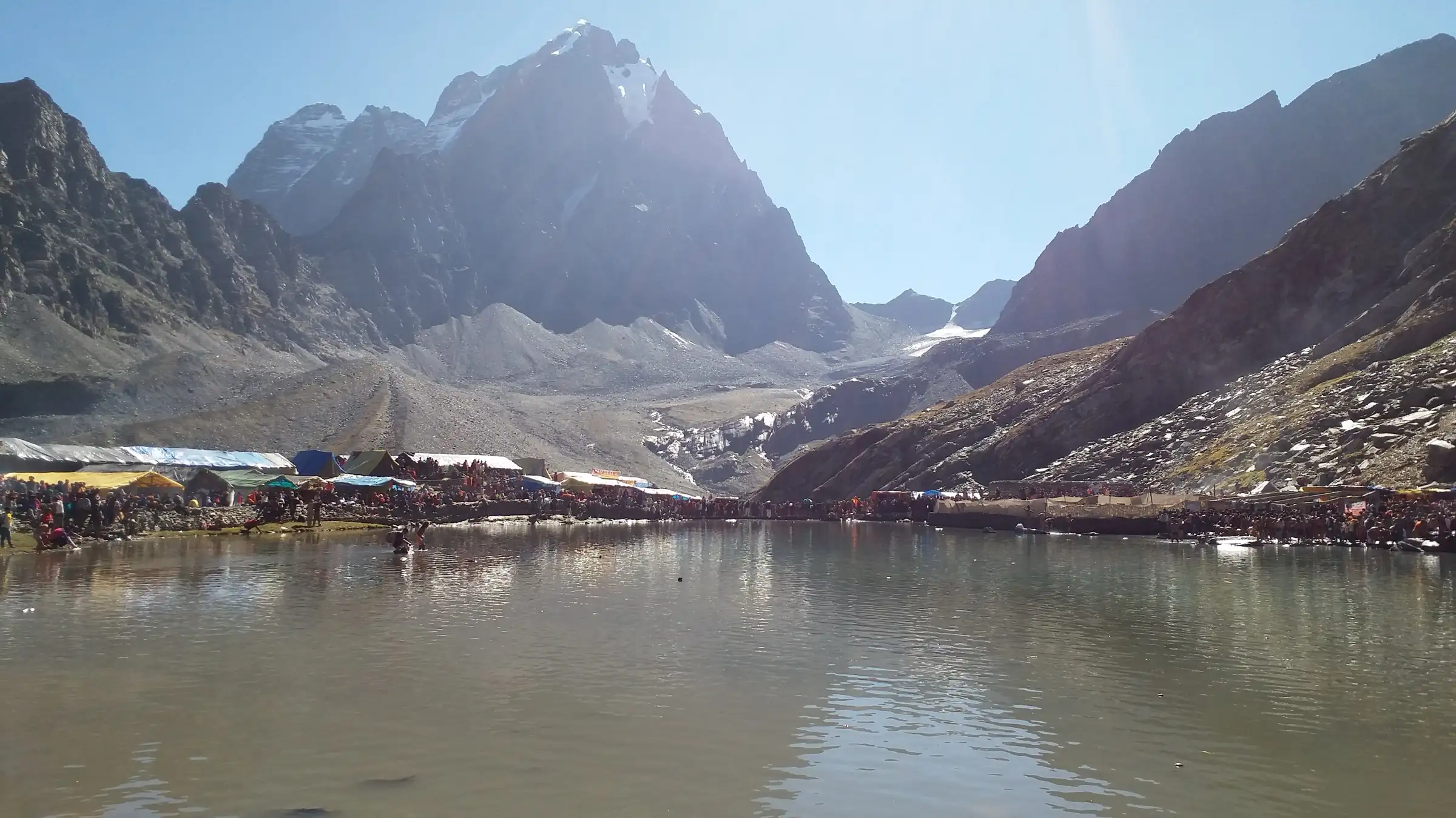 Manimahesh Lake with pilgrims' tents along its shore below the rocky Manimahesh Kailash peak