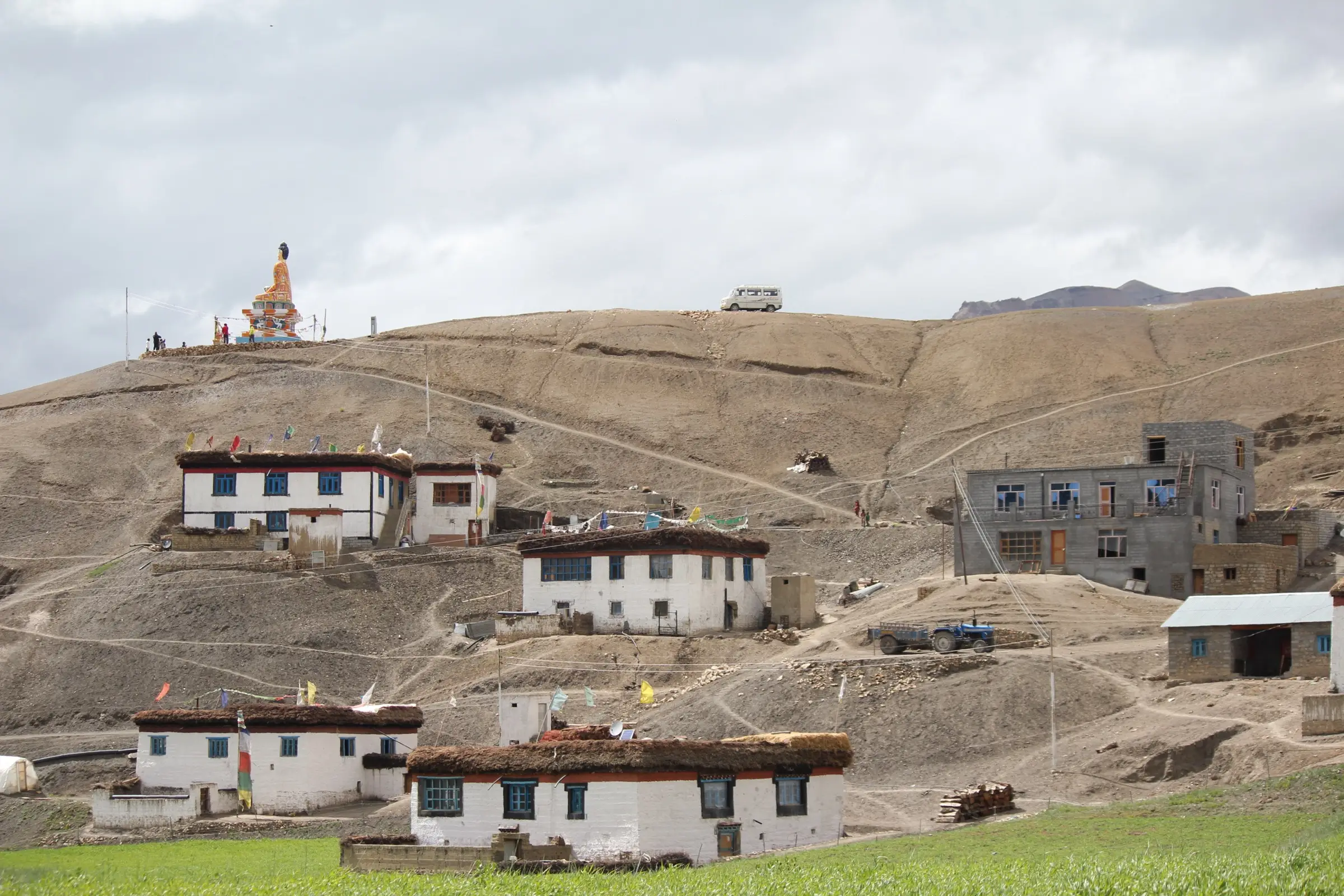 White mud-brick houses of Langza village with the large Buddha statue on the brown hill above, the start of the trek