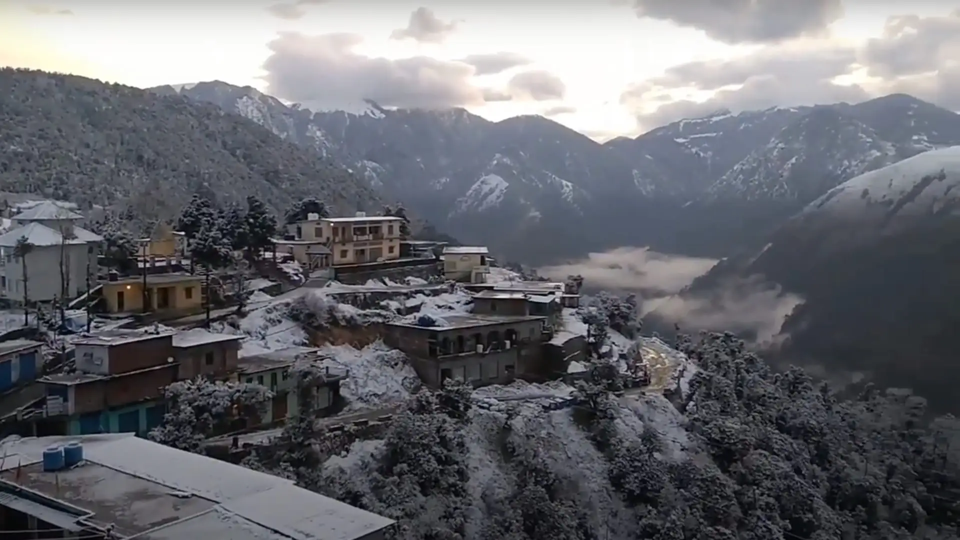 Lohajung village, the start of the Ajan Top walk, with snow on rooftops and trees and snowy ridges behind in January