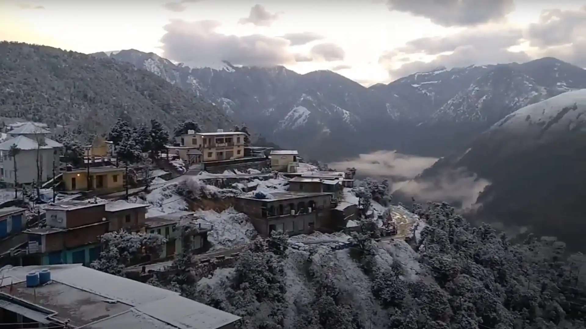 Lohajung village, the start of the Ajan Top walk, with snow on rooftops and trees and snowy ridges behind in January