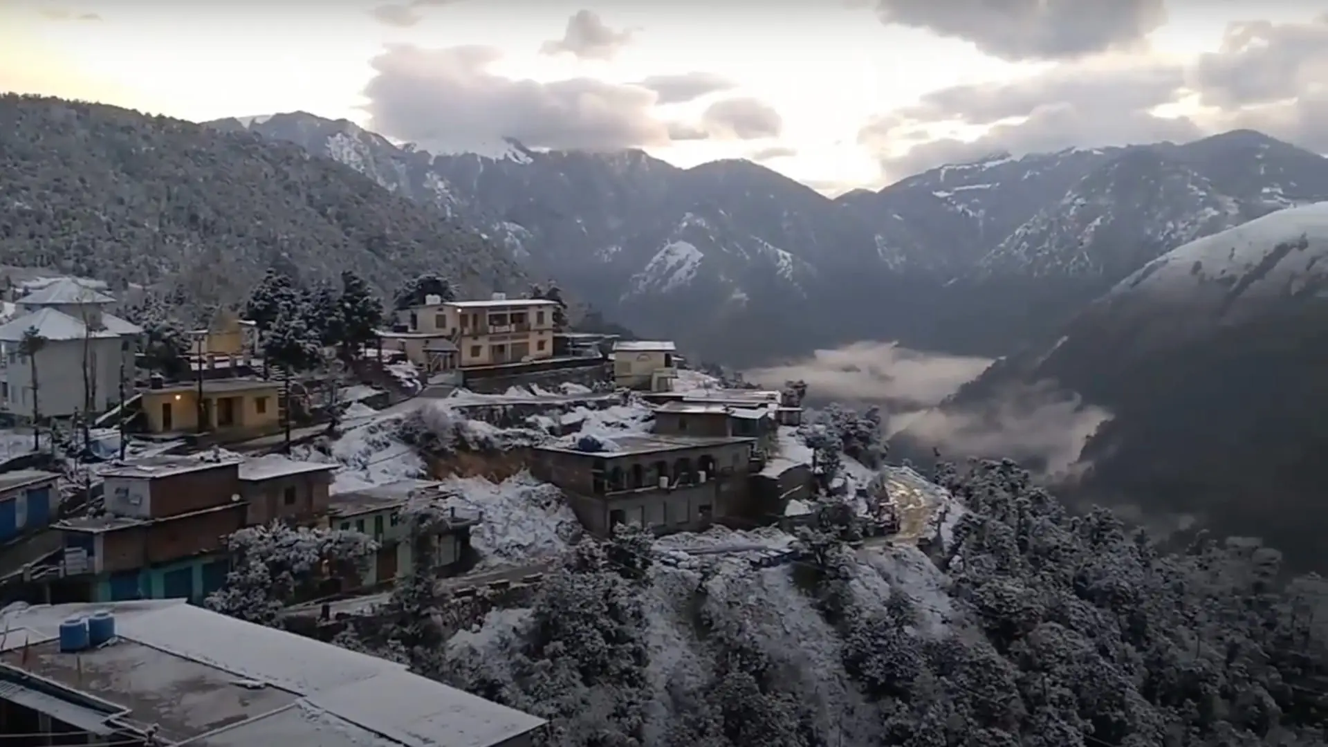 Lohajung village, the start of the Ajan Top walk, with snow on rooftops and trees and snowy ridges behind in January