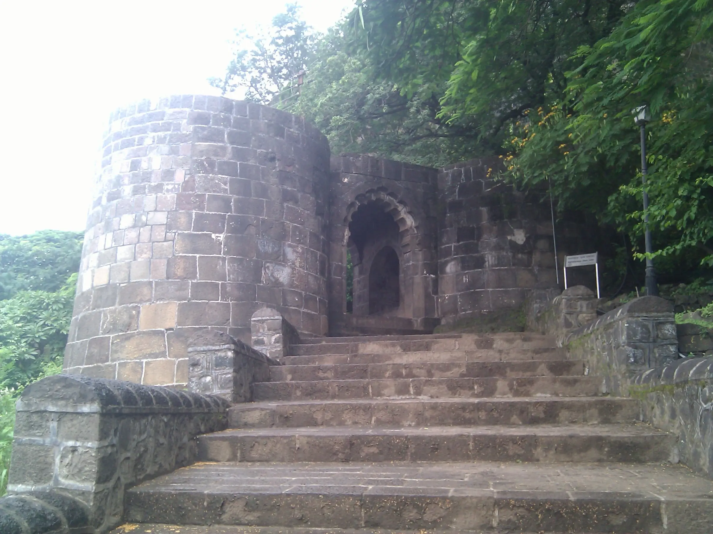 Stone steps leading up to the Mahadarwaja, the first gate of Shivneri Fort, beside a round bastion