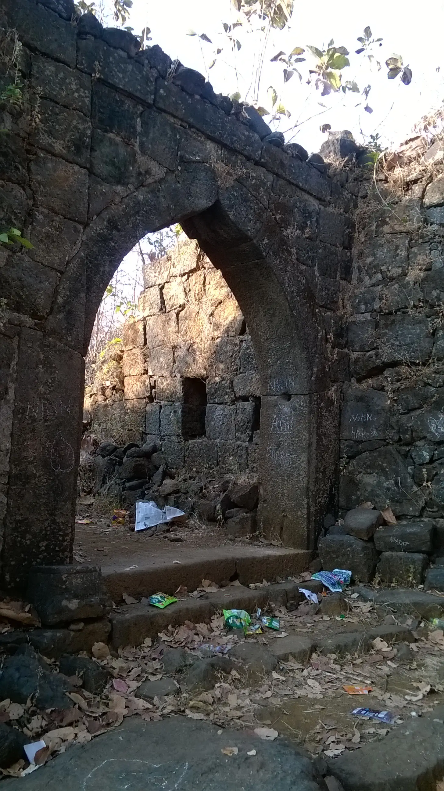 Stone arch of the main gate of Avchitgad fort with ruined walls behind it